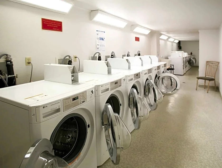 Row of front-loading washing machines in a laundromat.