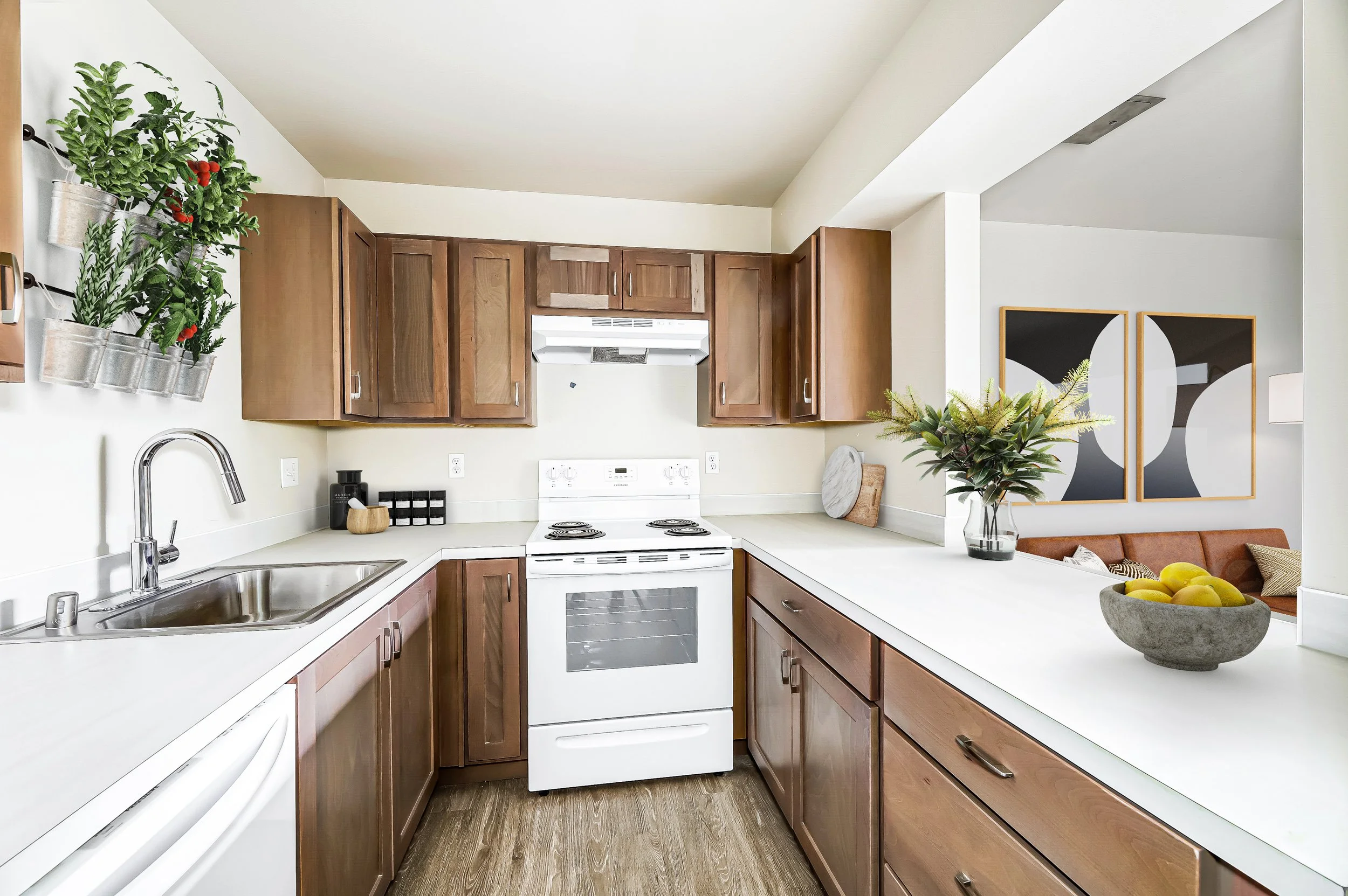 Kitchen with wooden cabinets, white stove, white countertop, plants, and artwork on the wall.