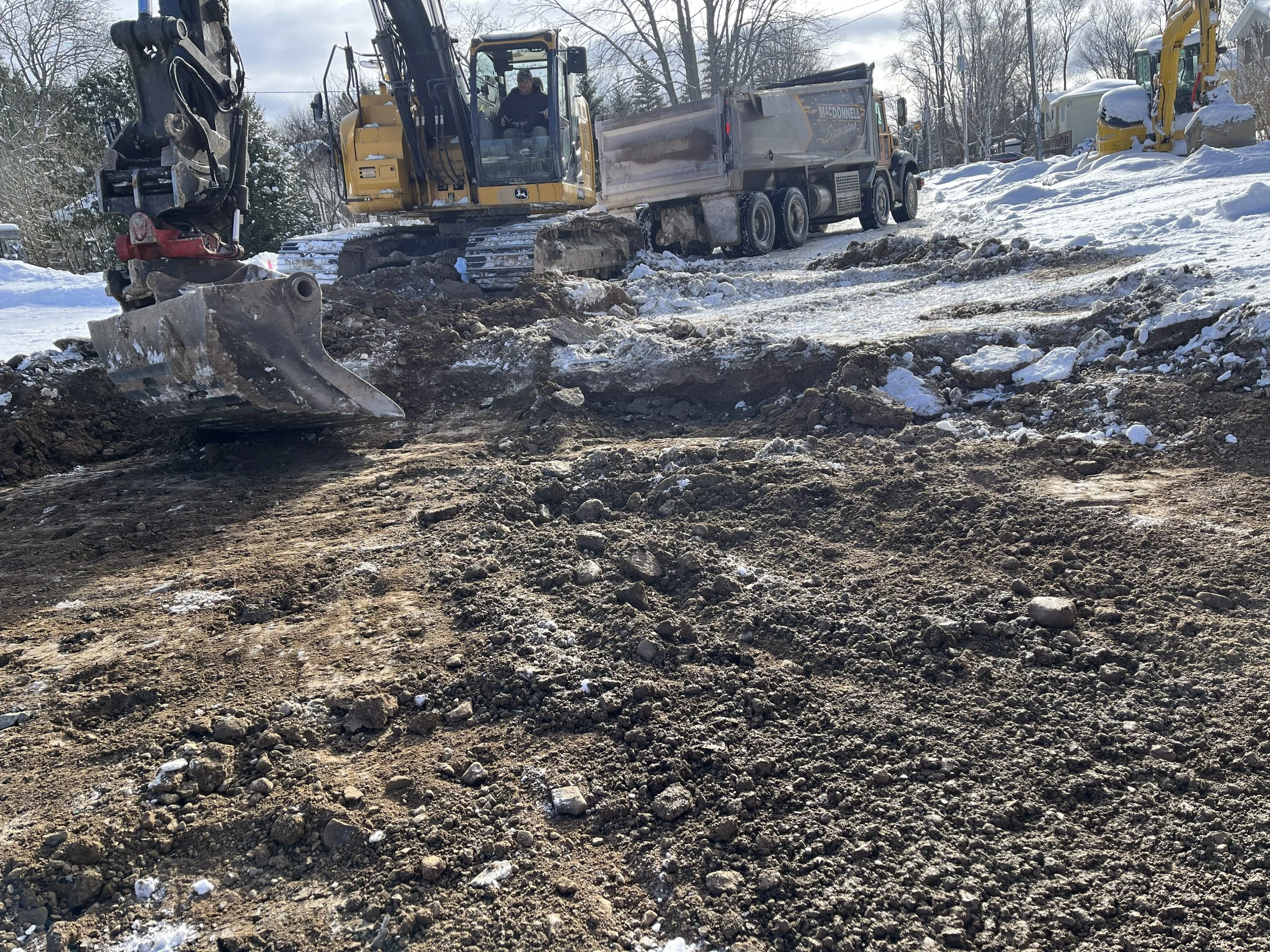 Construction site with excavator and dump truck working on snowy ground