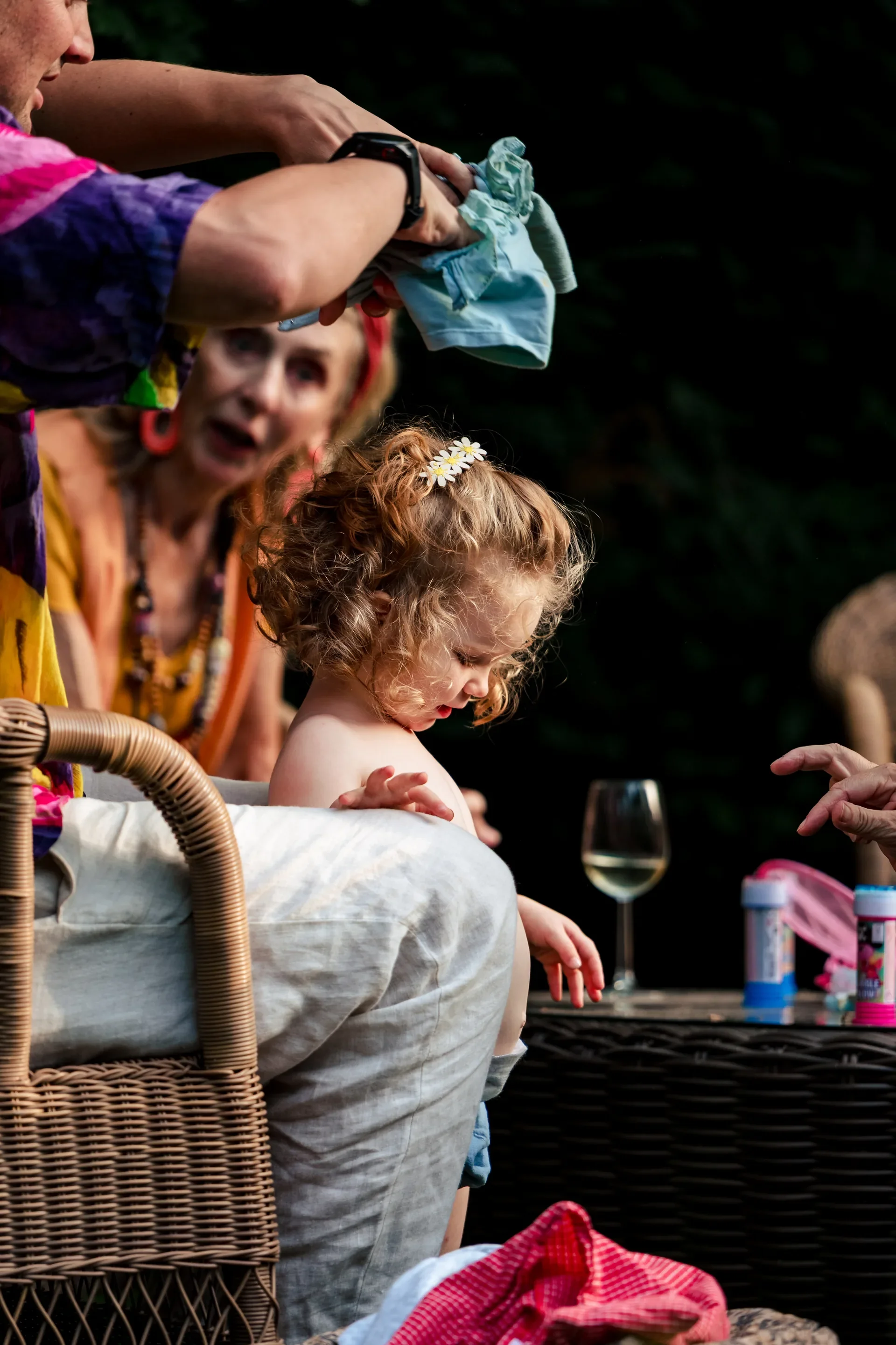 Kinder krijgt haar gezicht geschminkt tijdens een feestje, met volwassenen die toekijken en champagne glazen op tafel.
