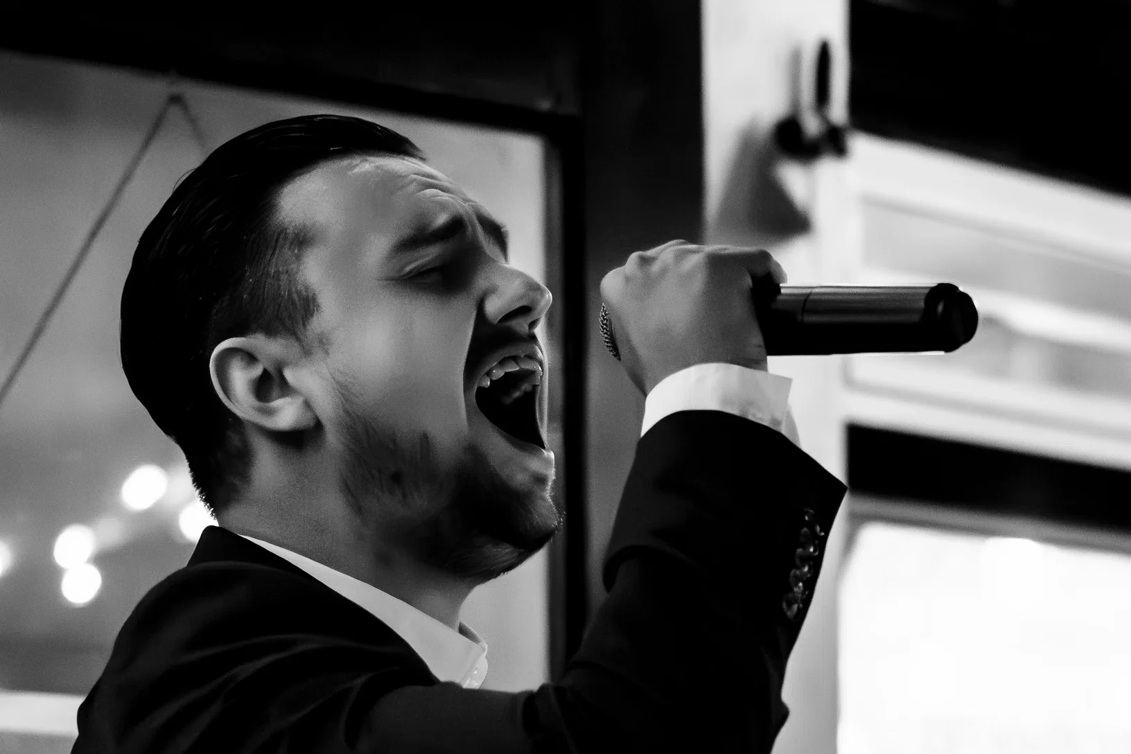 Man in een pak zingt met microfoon in hand, zwart-wit foto