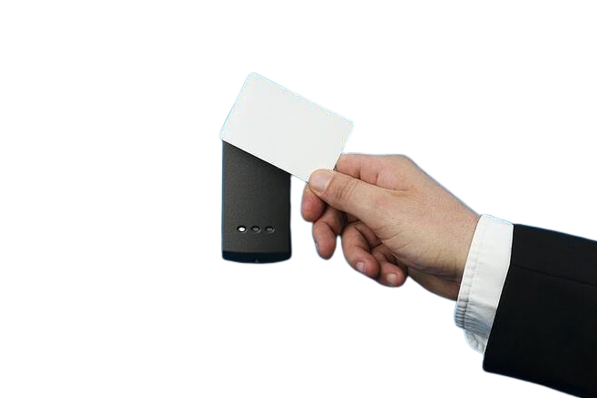 A person in a business suit holding a white card near a small black device on a dark background.