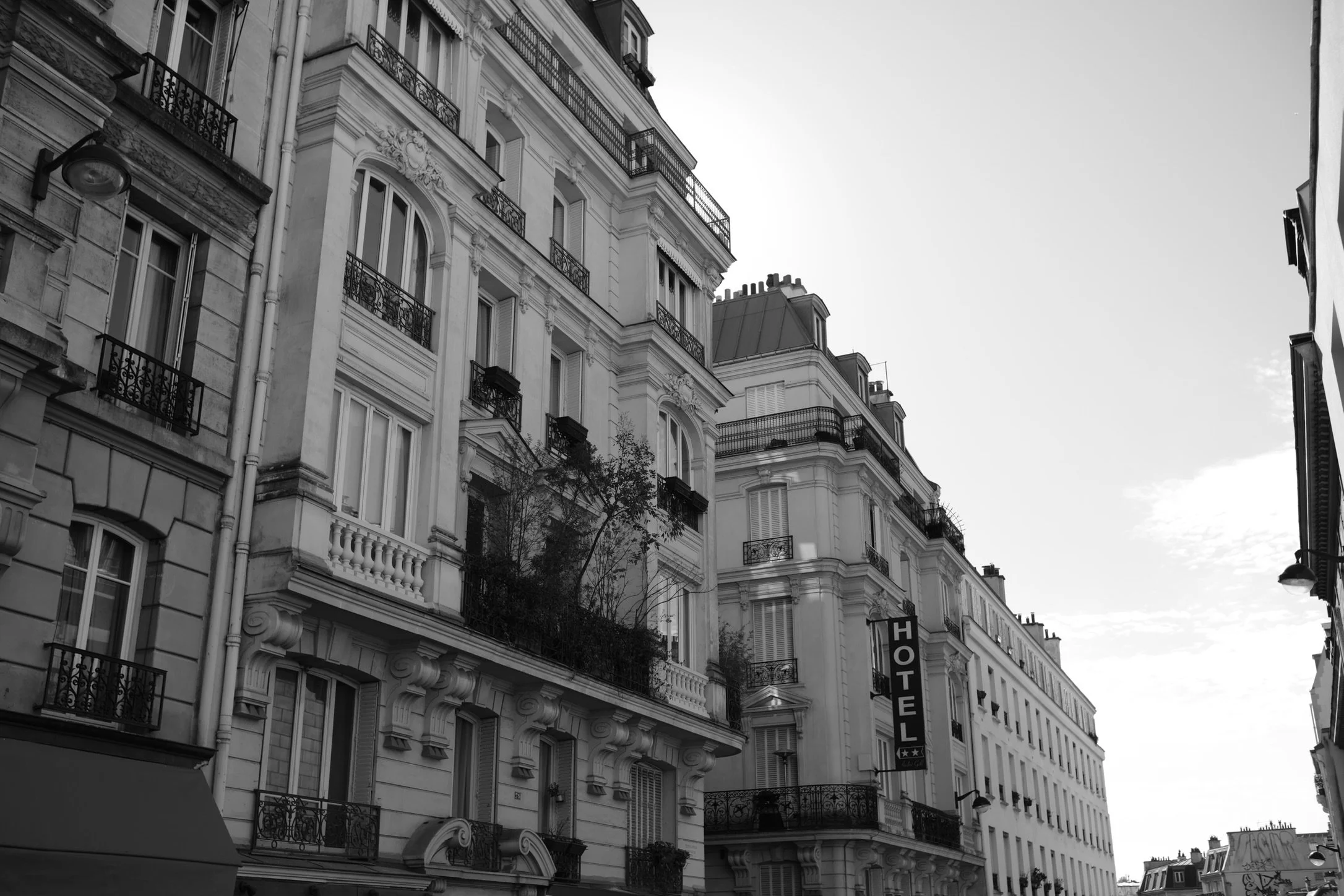 Black and white photo of Parisian apartment buildings, with one sign indicating a hotel.
