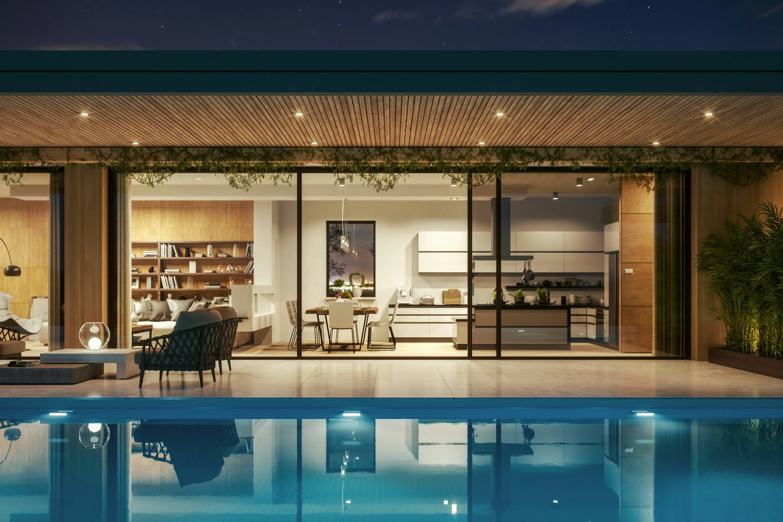 Modern house with large glass windows overlooking a swimming pool at night, with a cozy lit interior visible inside including a kitchen, dining area, and living room.