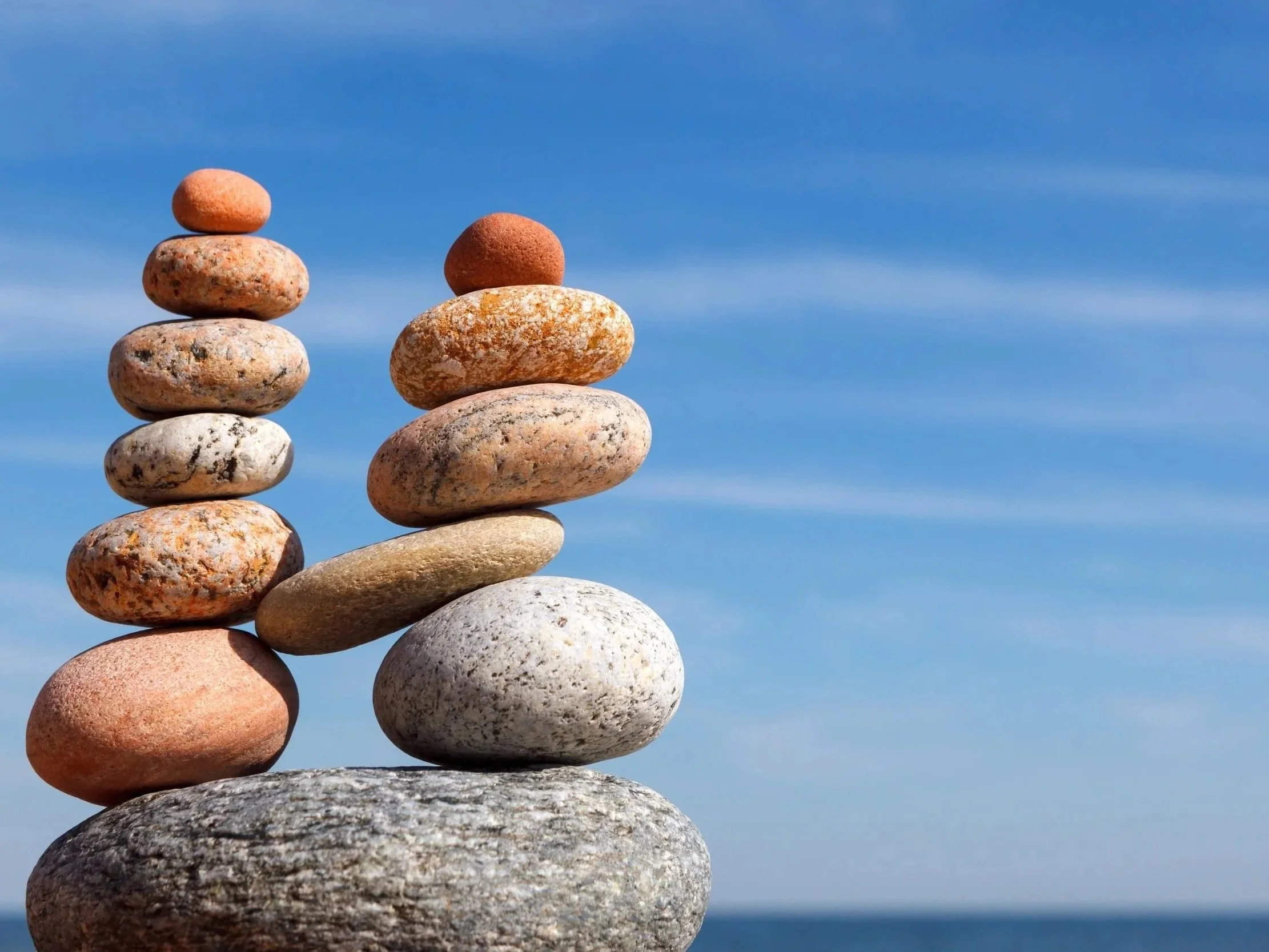 Due colonne di pietre di varia forma e colore, equilibrate le une sulle altre, contro un cielo azzurro con poche nuvole.