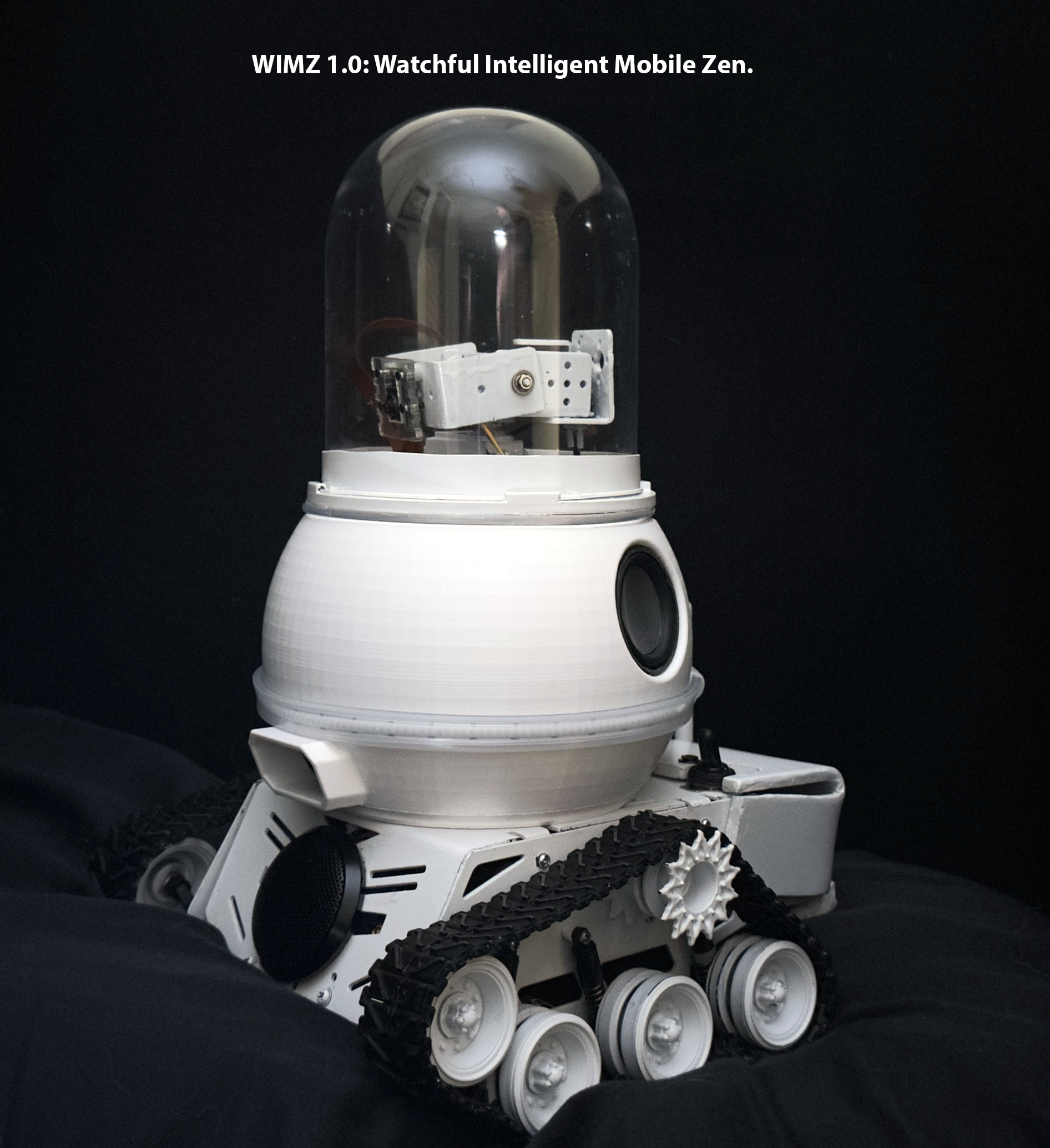 A small robot with tank-like tracks and a white, rounded body and a clear dome top. The robot has a speaker on its side and is set against a black background with the text 'WIMZ 1.0: Watchful Intelligent Mobile Zen.'