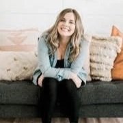A smiling woman sitting on a sofa in a cozy living room.