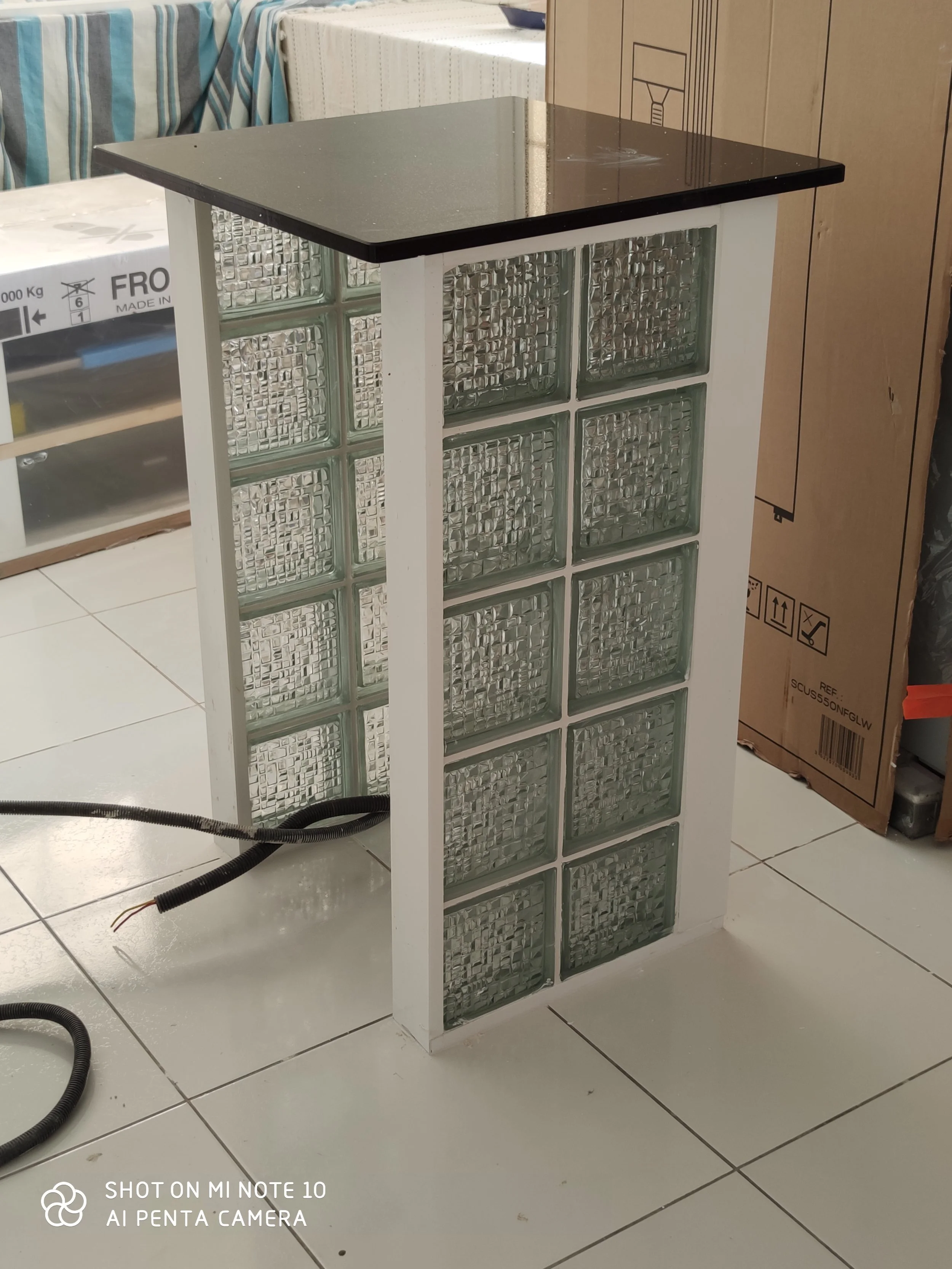 mini table en marbre noire, composée de brique de verre et d'une structure en plastique blanc, placé dans la cuisine.