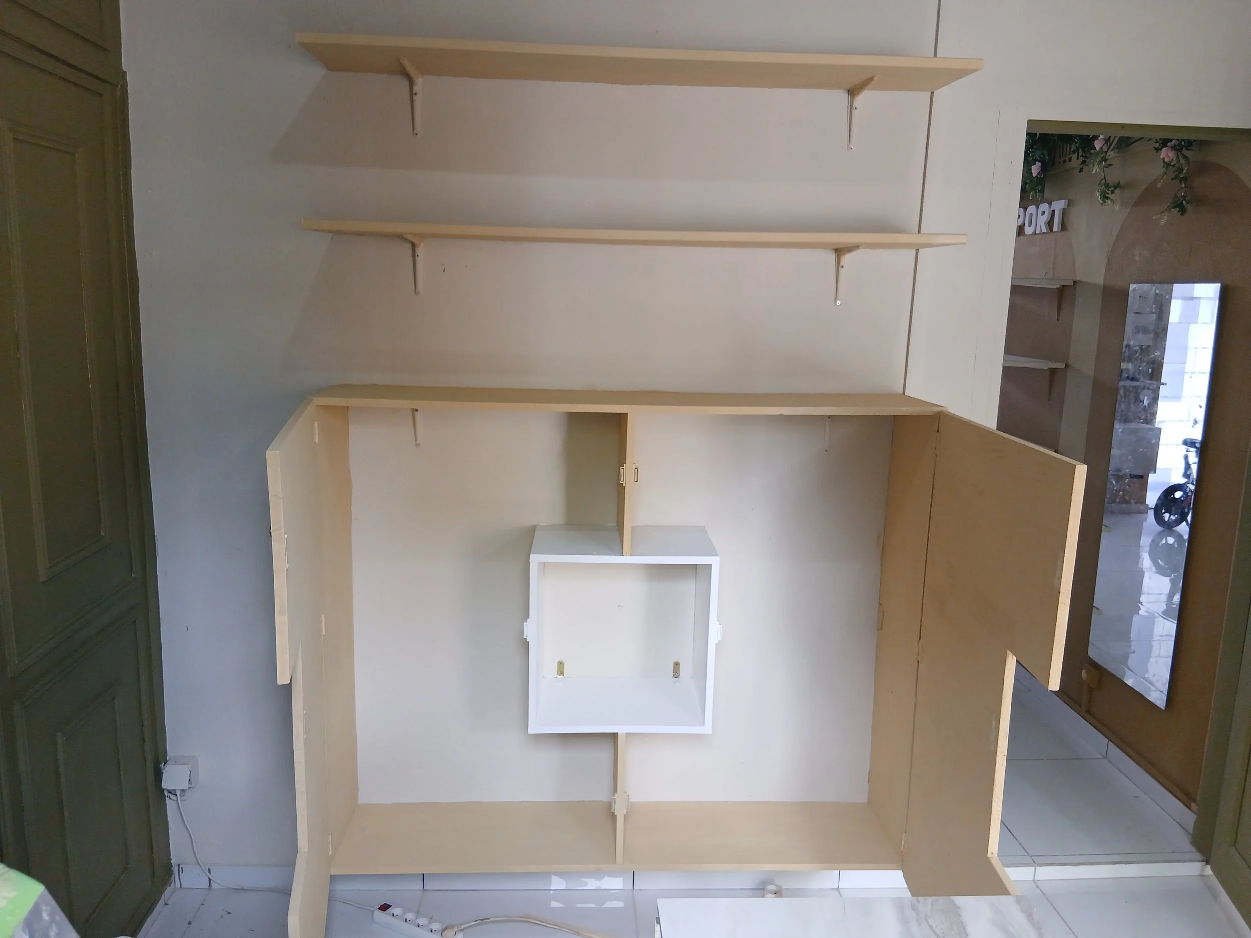 Une pièce avec des étagères en bois fixées au mur et un meuble en bois avec une porte ouverte, vue de dessus.