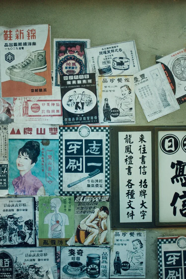 A wall decorated with vintage Chinese advertisements, posters, and signs featuring Chinese characters, illustrations of products