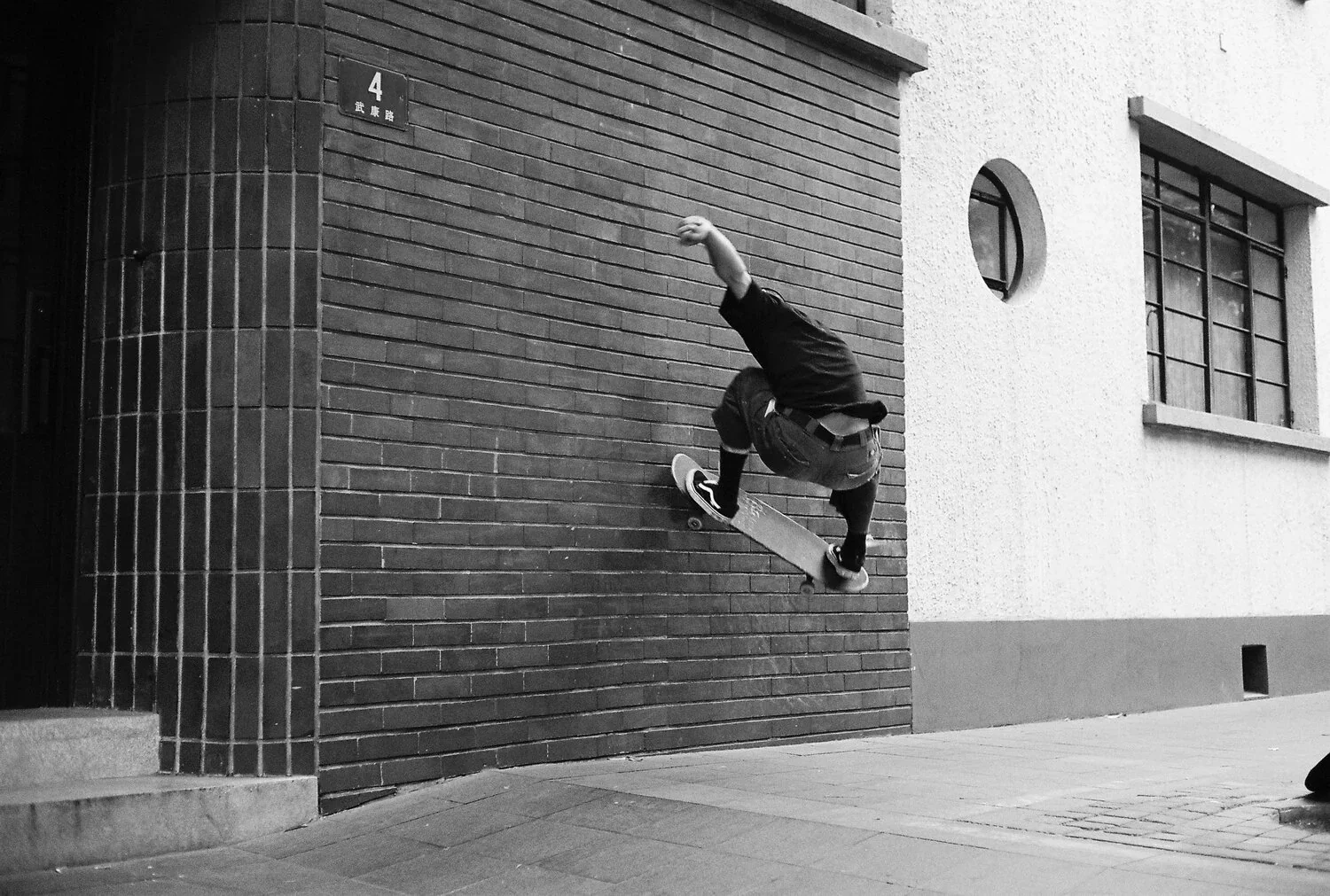 A person skateboarding on a brick wall in an urban setting, captured mid-air during a trick.