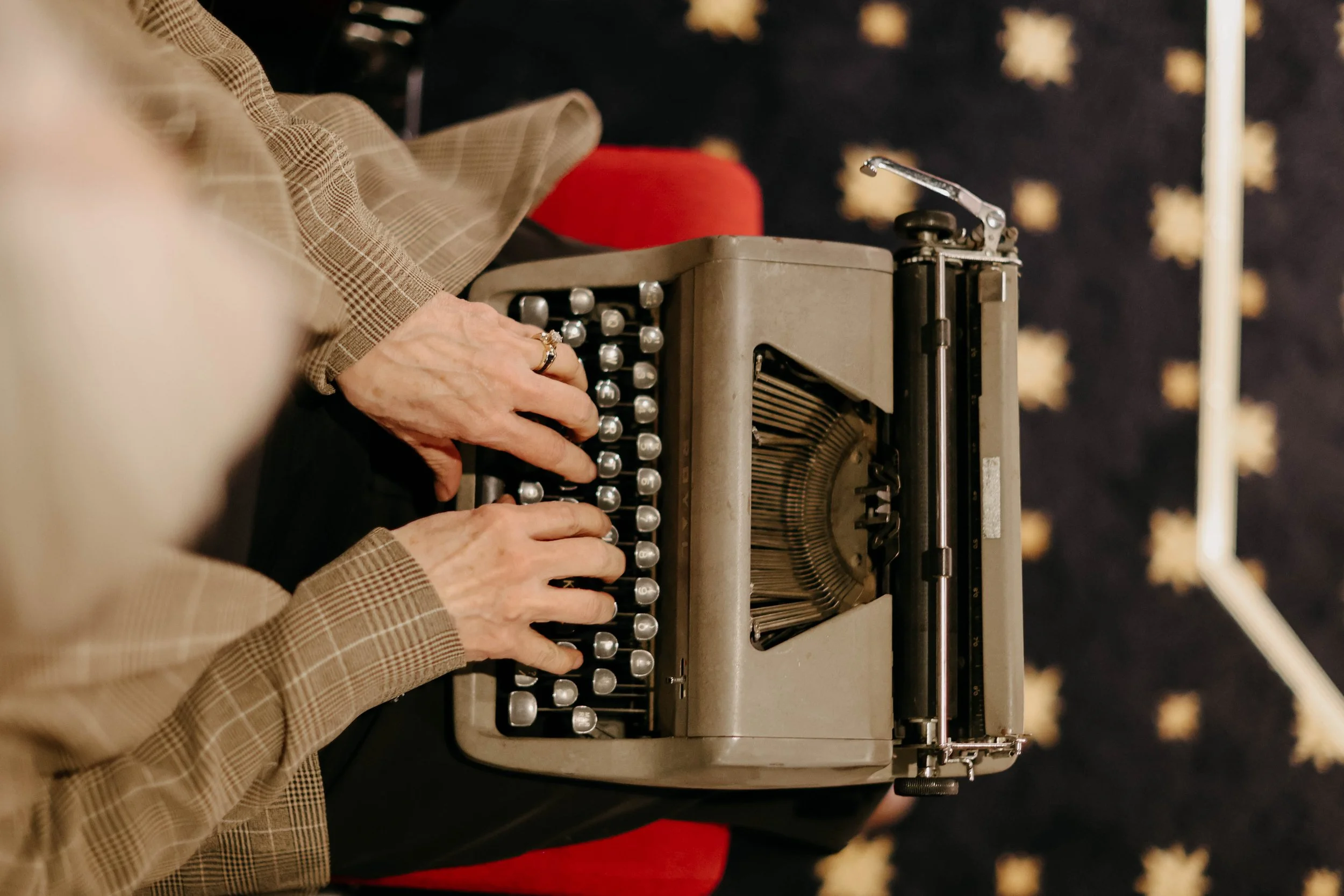Close-up of elderly person's hands typing on a vintage typewriter.