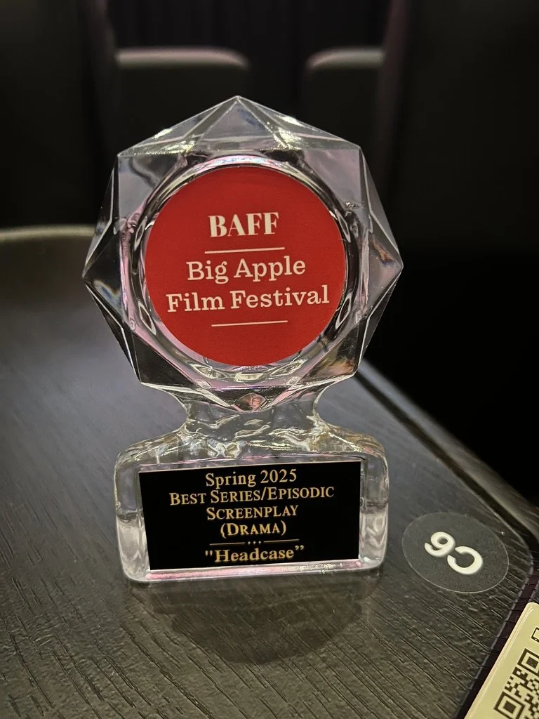Crystal award with red circular inset reading "BAFF Big Apple Film Festival," and black plaque with gold text stating, "Spring 2025 Best Series/Episodic Screenplay (Drama) 'Headcase'".