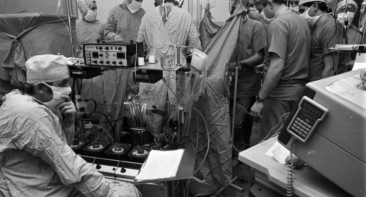 Medical professionals in a hospital operating room performing a surgical procedure, with advanced medical equipment and monitors surrounding them.