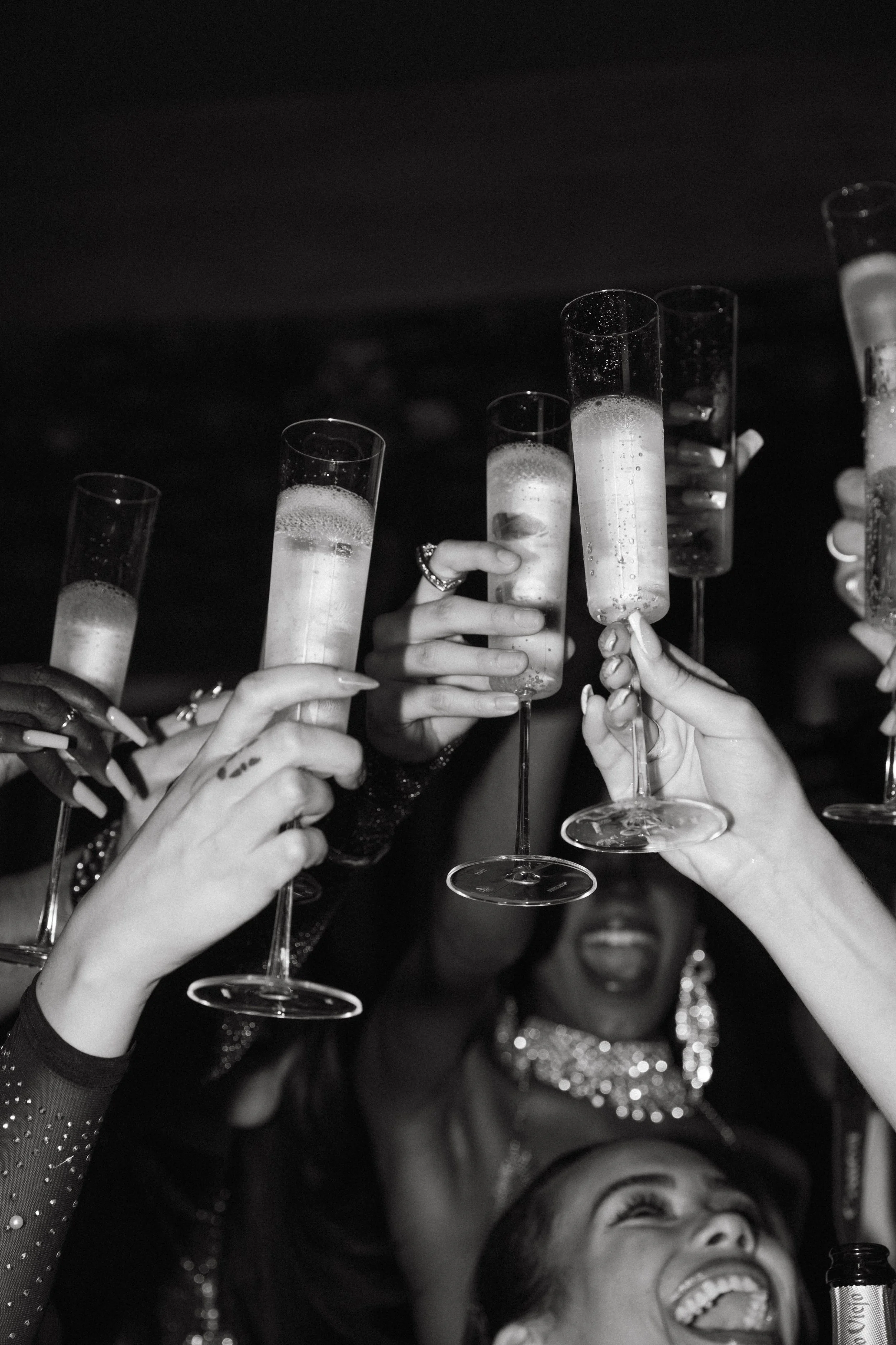 A group of women celebrating with champagne glasses raised in a toast at a party or celebration, smiling and enjoying the moment.