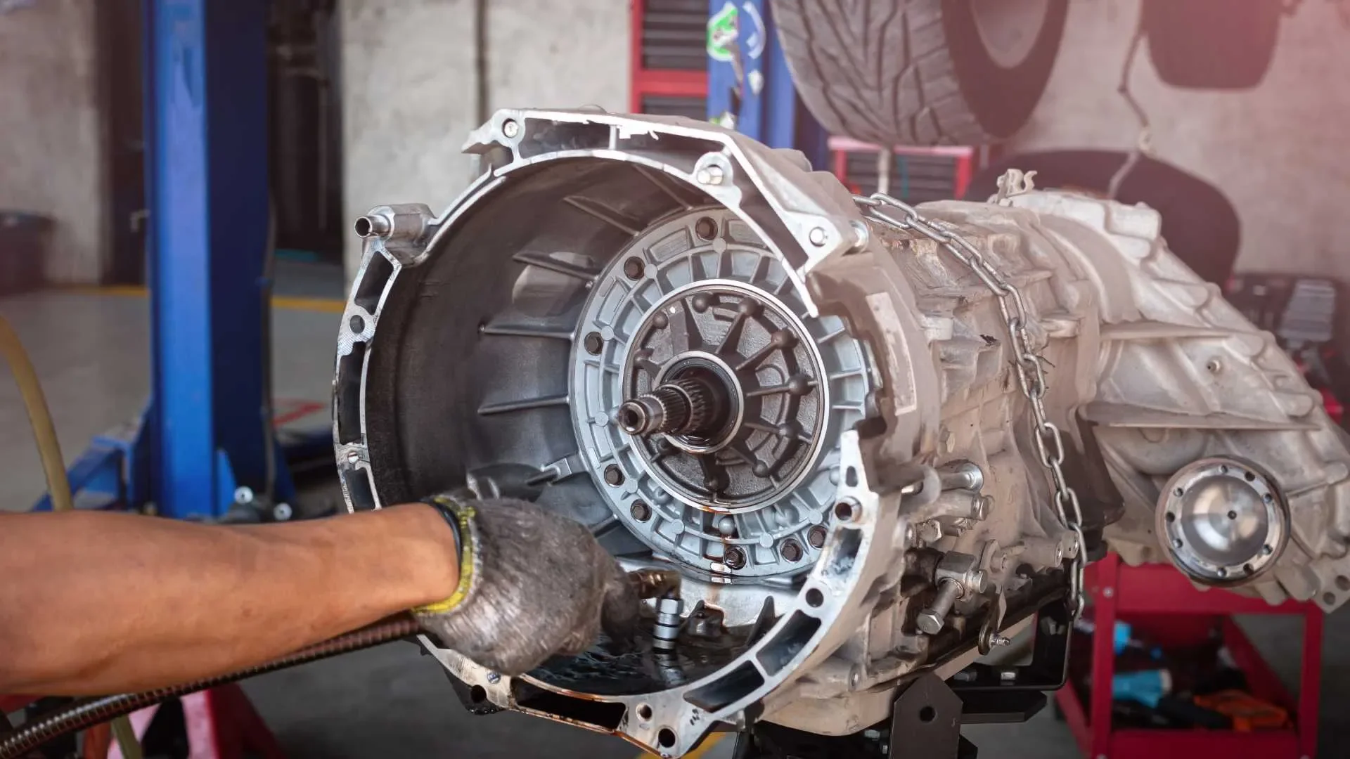Mechanic working on a car transmission in a garage.