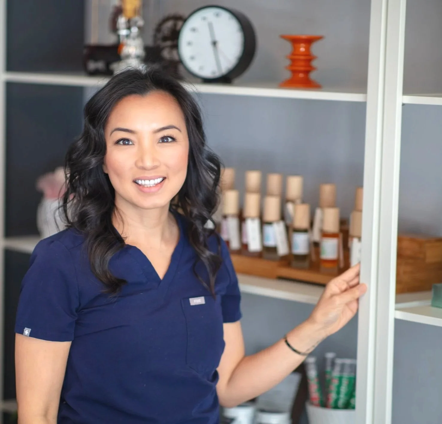 Anna Mai - Award winning acupuncturist serving Bay Area, CAf a shelf with bottles and jars, smiling at the camera.