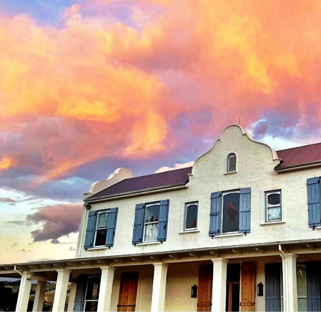 The Oneiric homestead under a colourful sunset sky with orange and purple clouds at sunset.