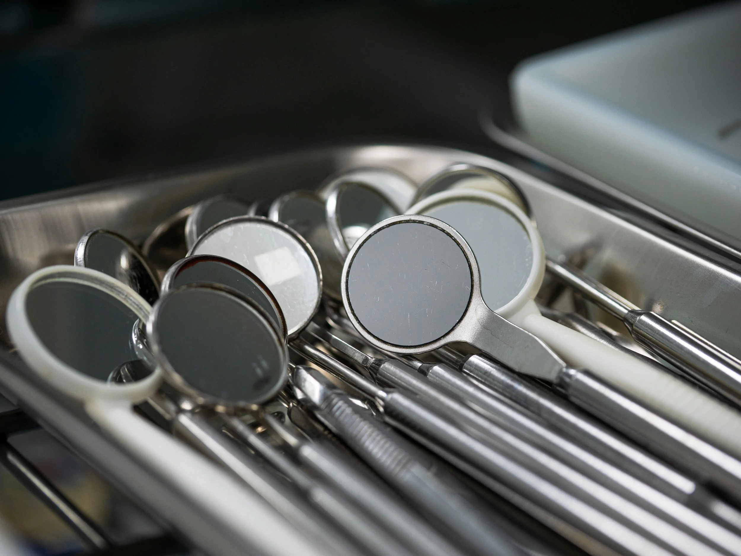Close-up view of multiple mirrored, dental tools with reflective surfaces, placed on a steel tray.