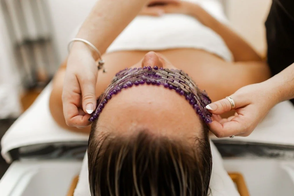 Person receiving a neck massage with electronic stimulation therapy, lying down with a white towel.