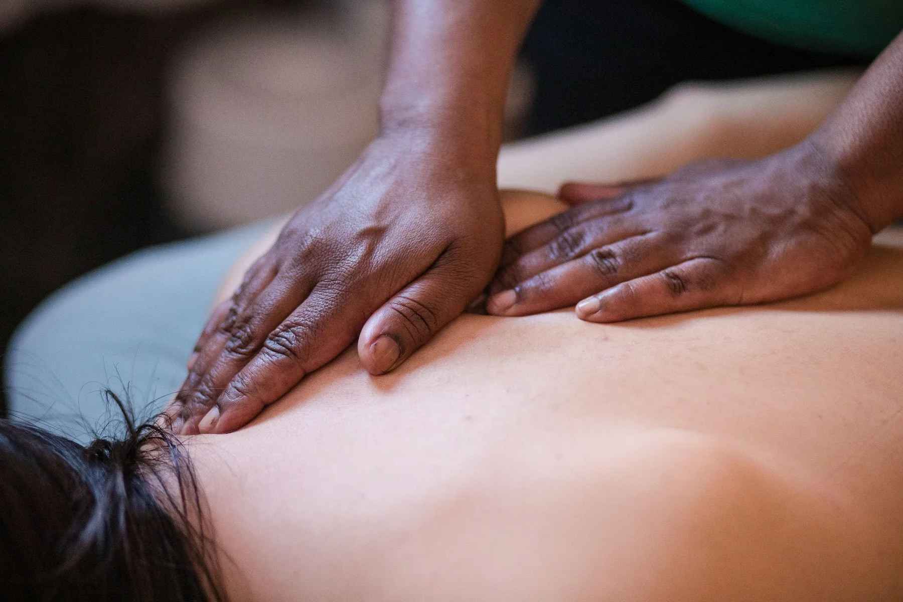 Close-up of a person giving a massage on someone's back, showing hands applying pressure on bare skin.