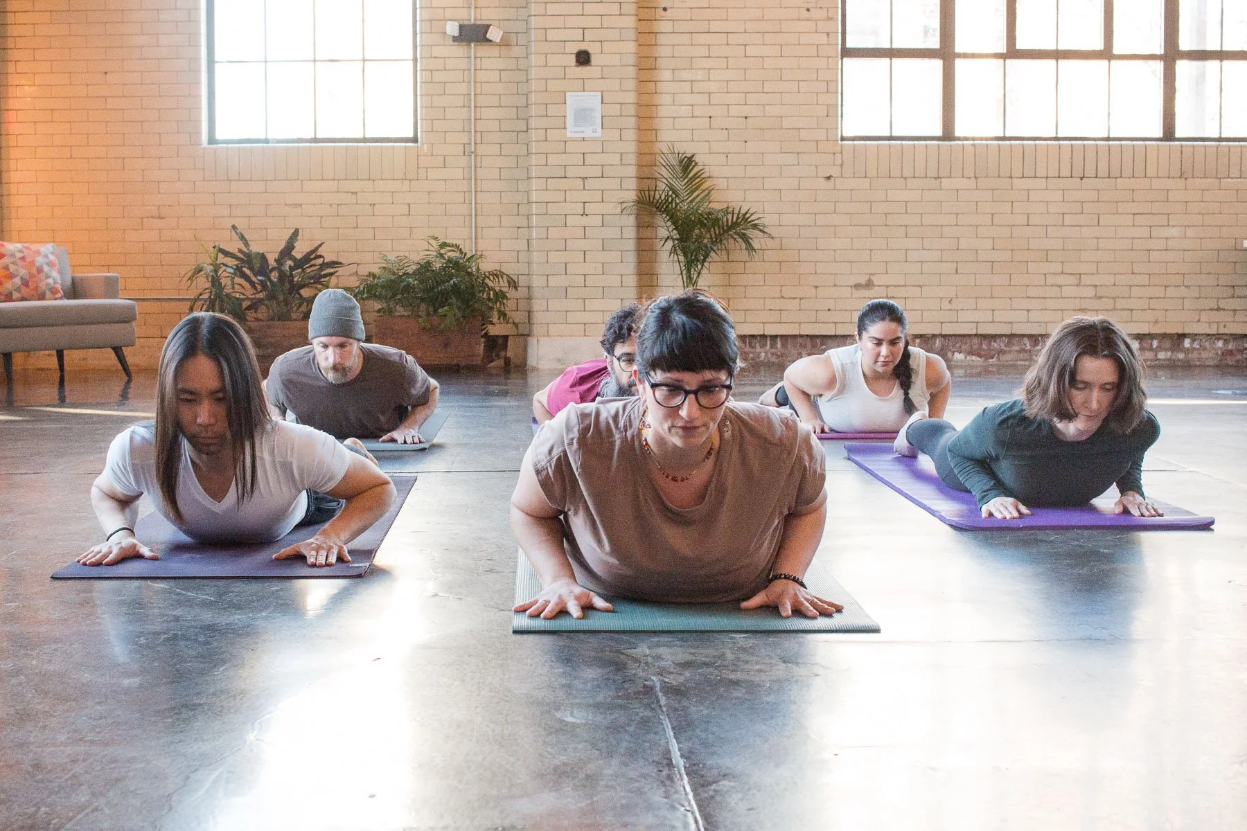 Group of people practicing yoga in a studio, performing the upward push pose on yoga mats.