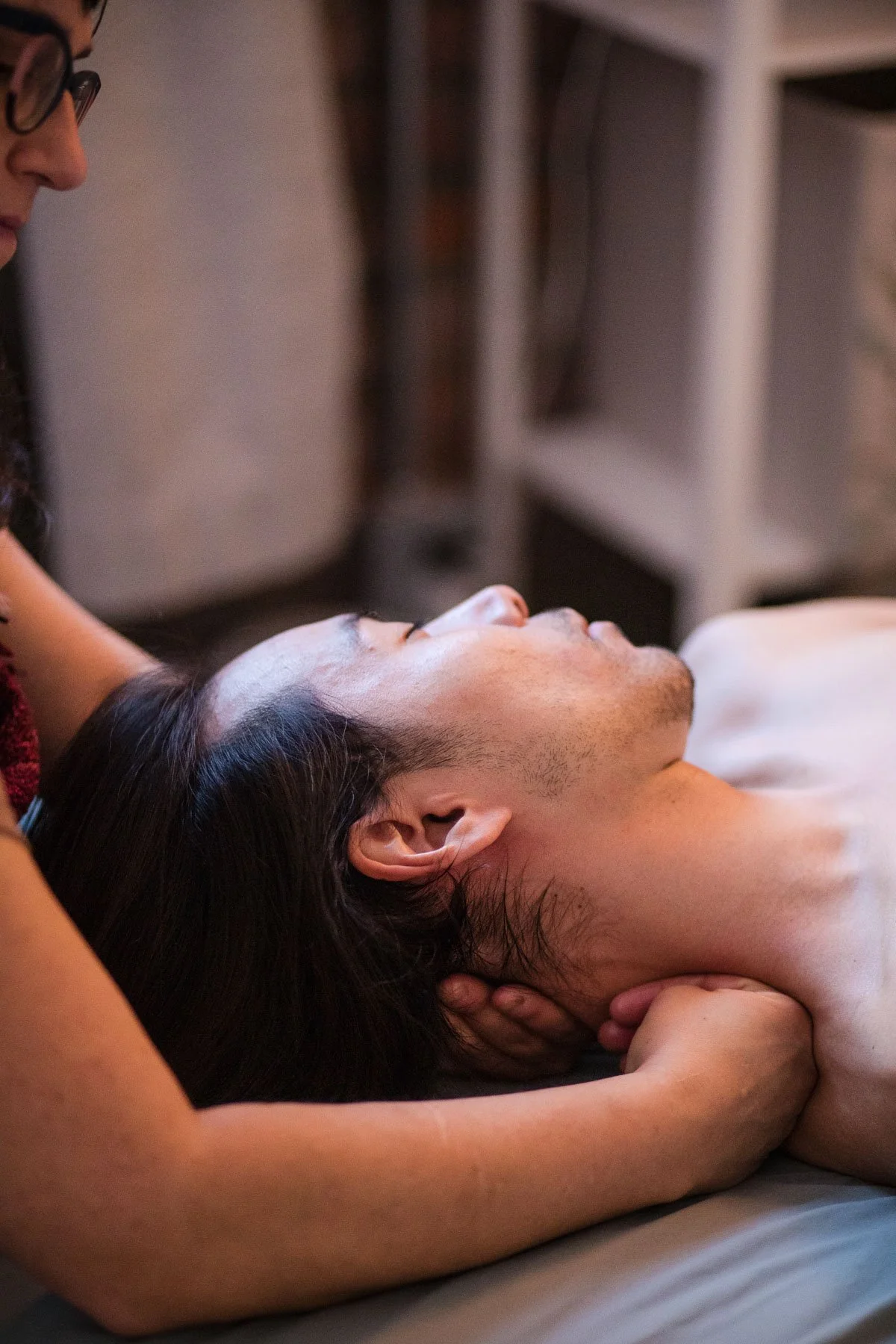A person receiving a massage with their eyes closed in a relaxed posture.