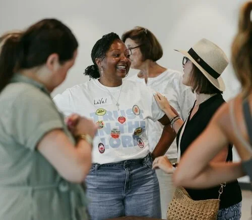 A group of women interacting and smiling at an indoor event.
