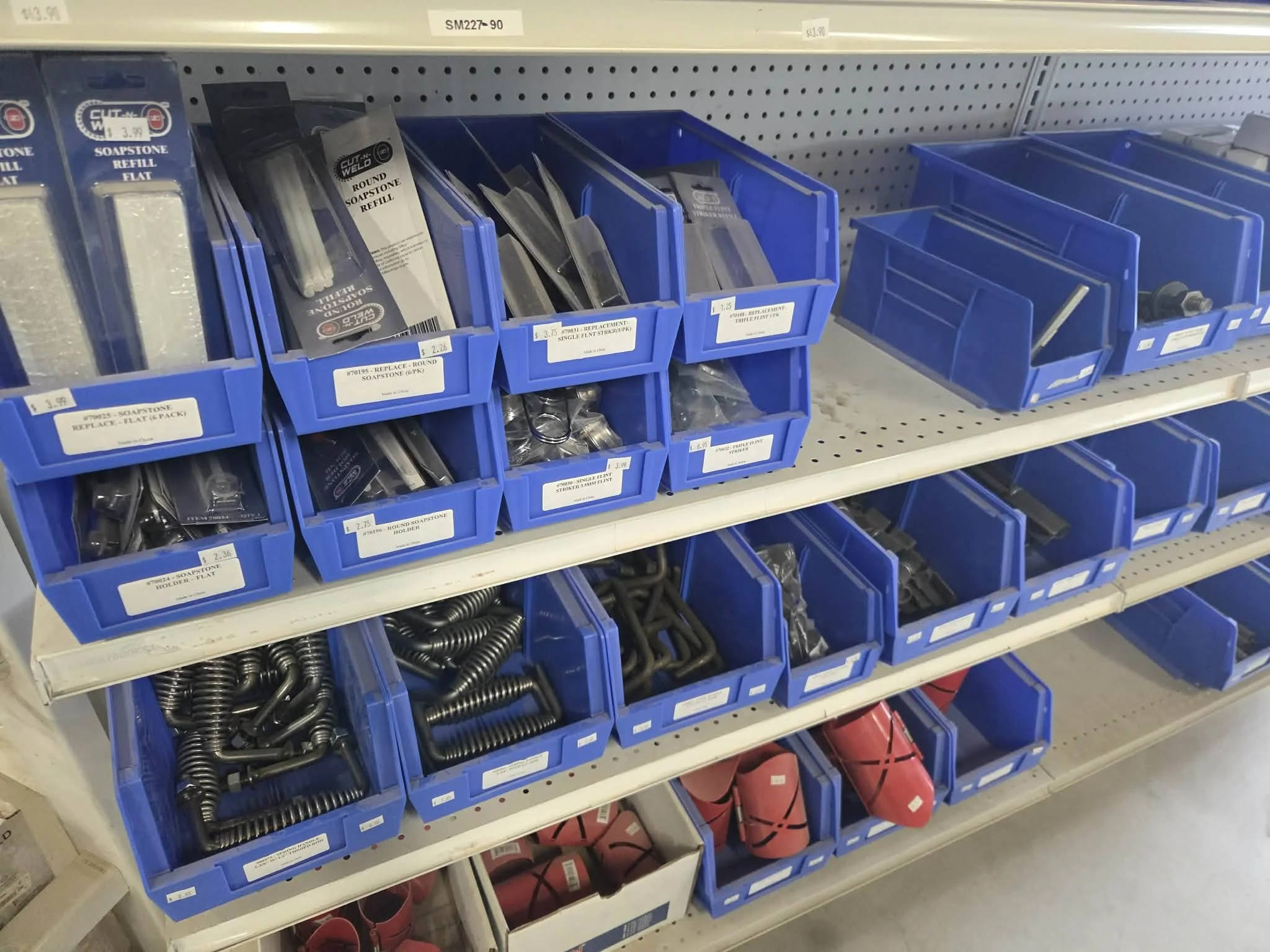 Hardware store shelves with blue plastic bins filled with various nails, screws, and fasteners.