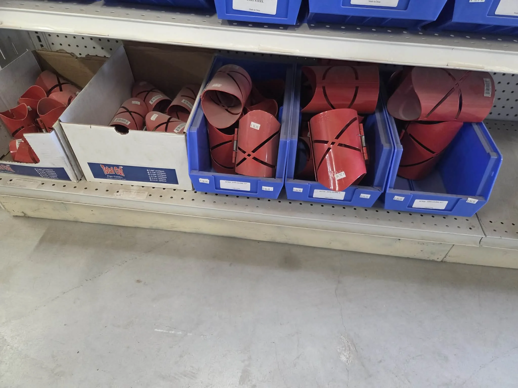 Shaft collars in red and black, stored in plastic bins and a cardboard box on a store shelf.