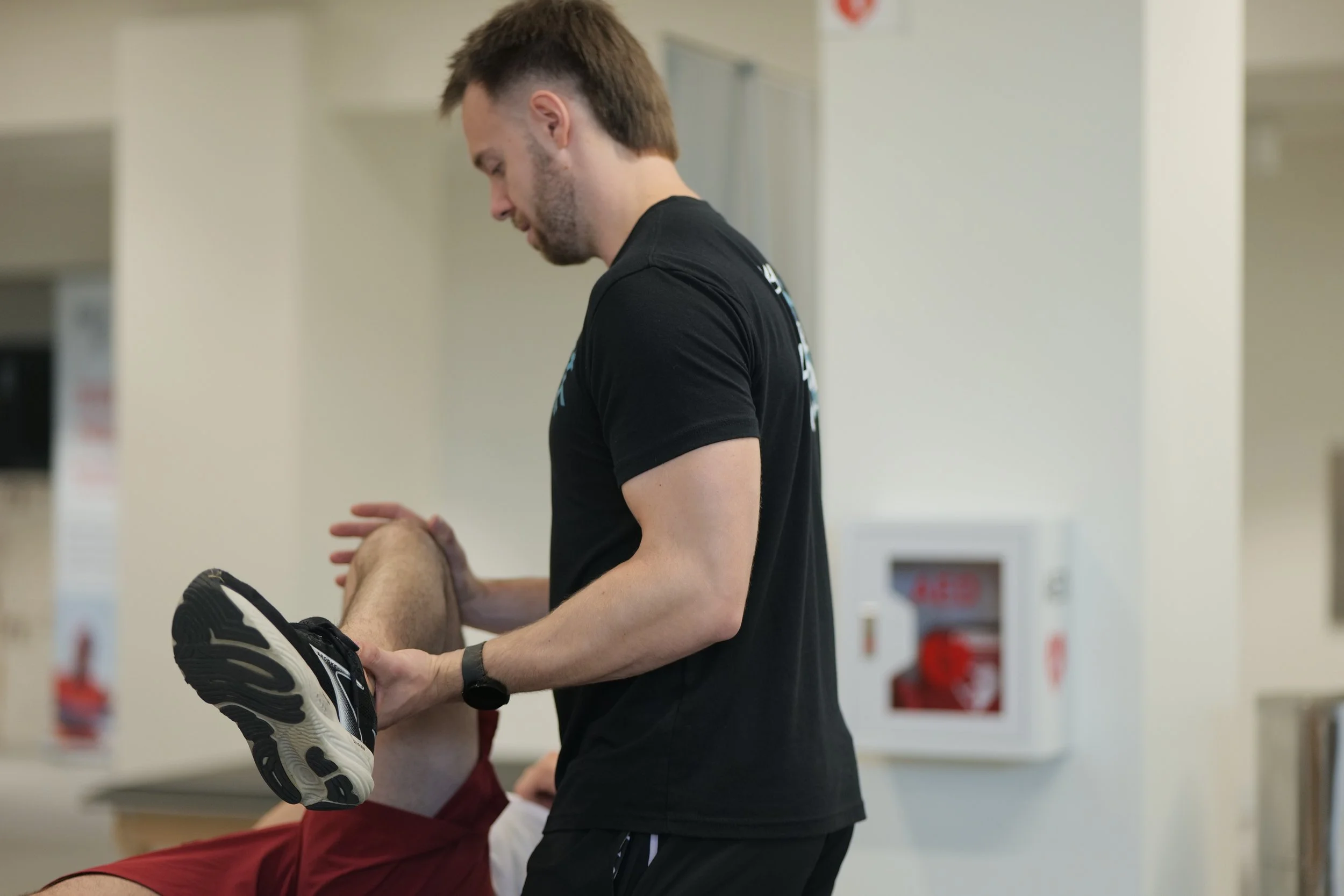 Physical Therapist performing stretching with a clients knee and leg, holding the client's leg during a rehabilitation session.