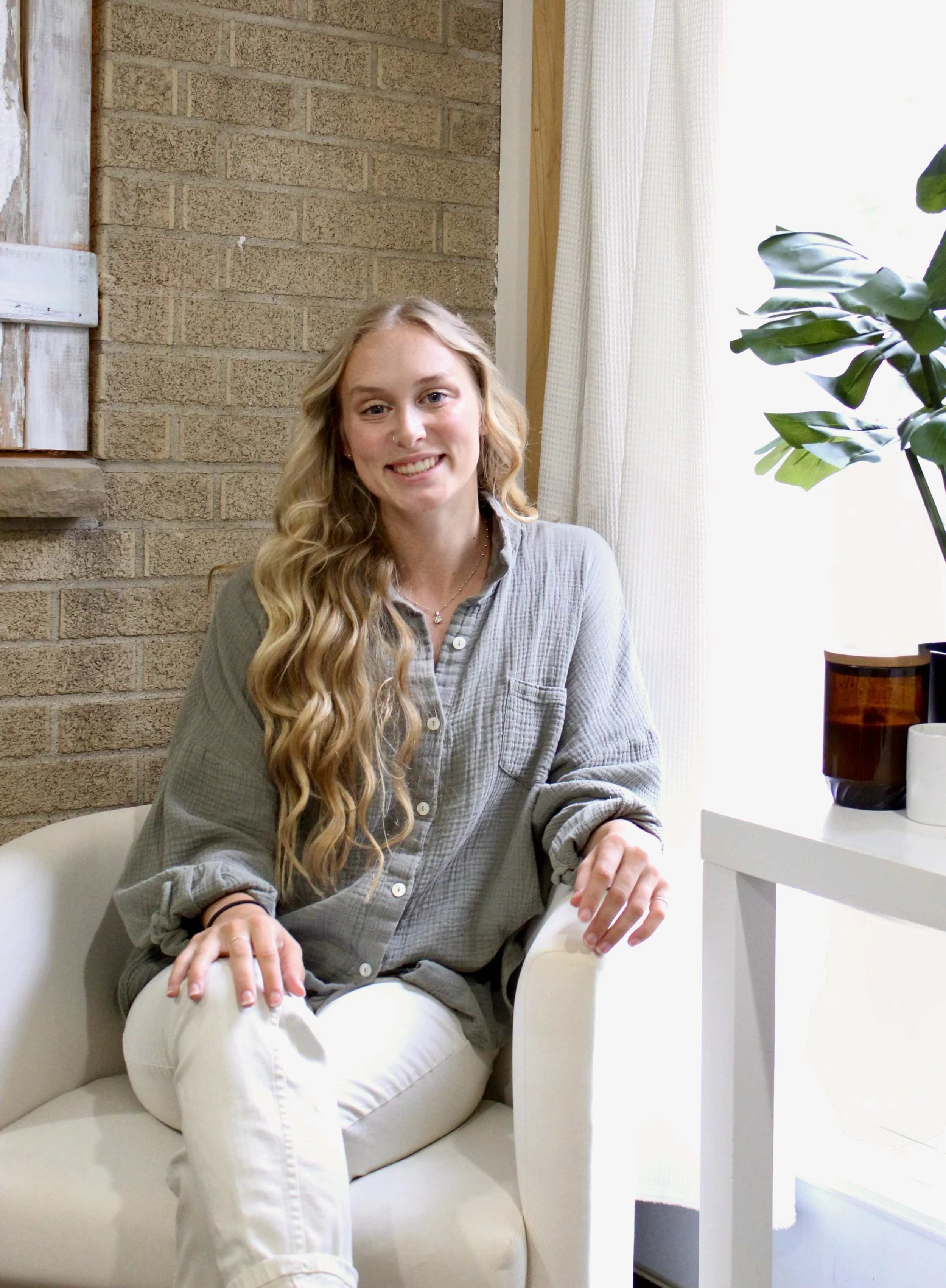 A young woman smiling and sitting in a chair in an office