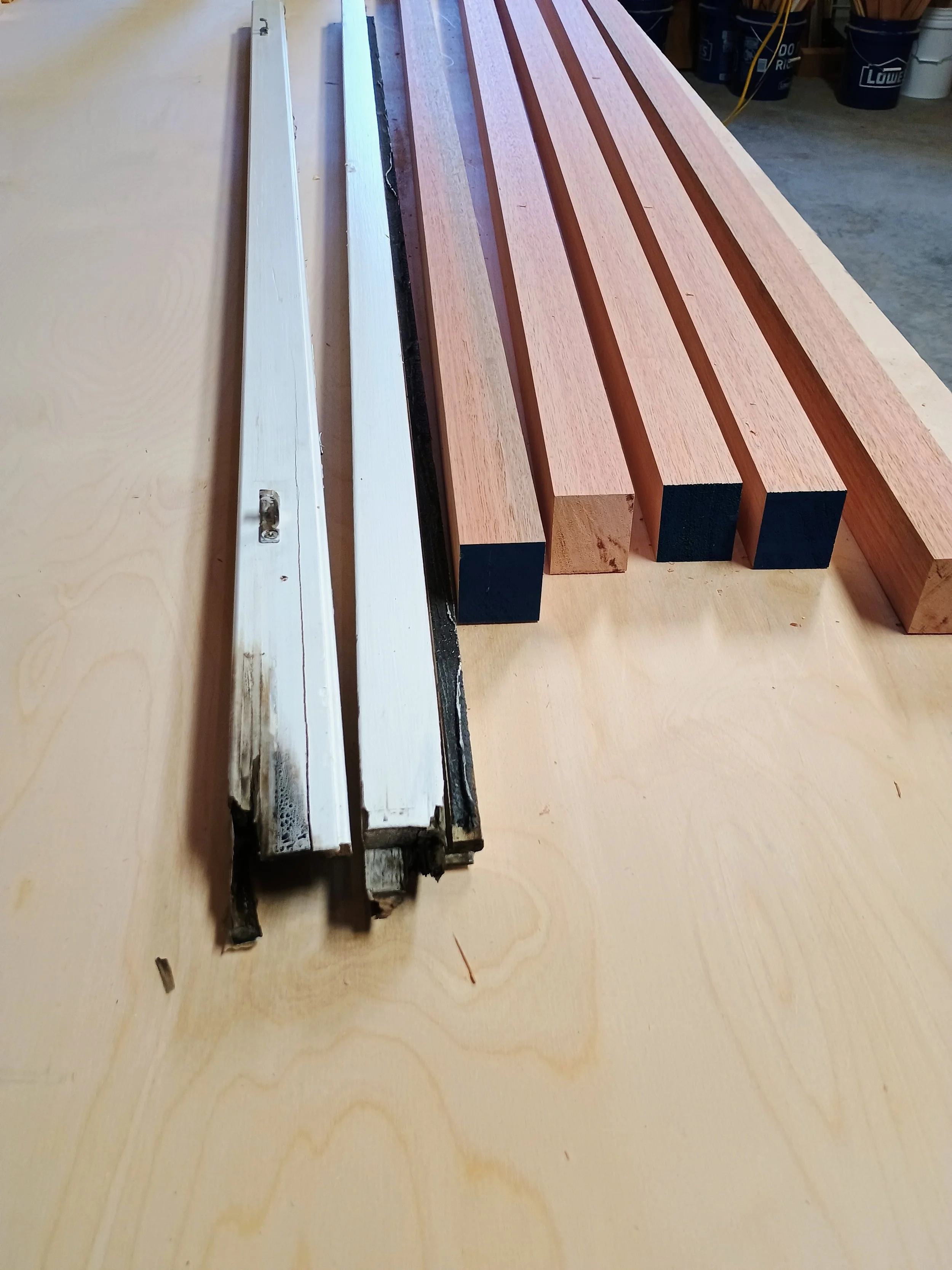 Wooden slats, some painted black, lined up on a workbench, with a partially disassembled window frame nearby.