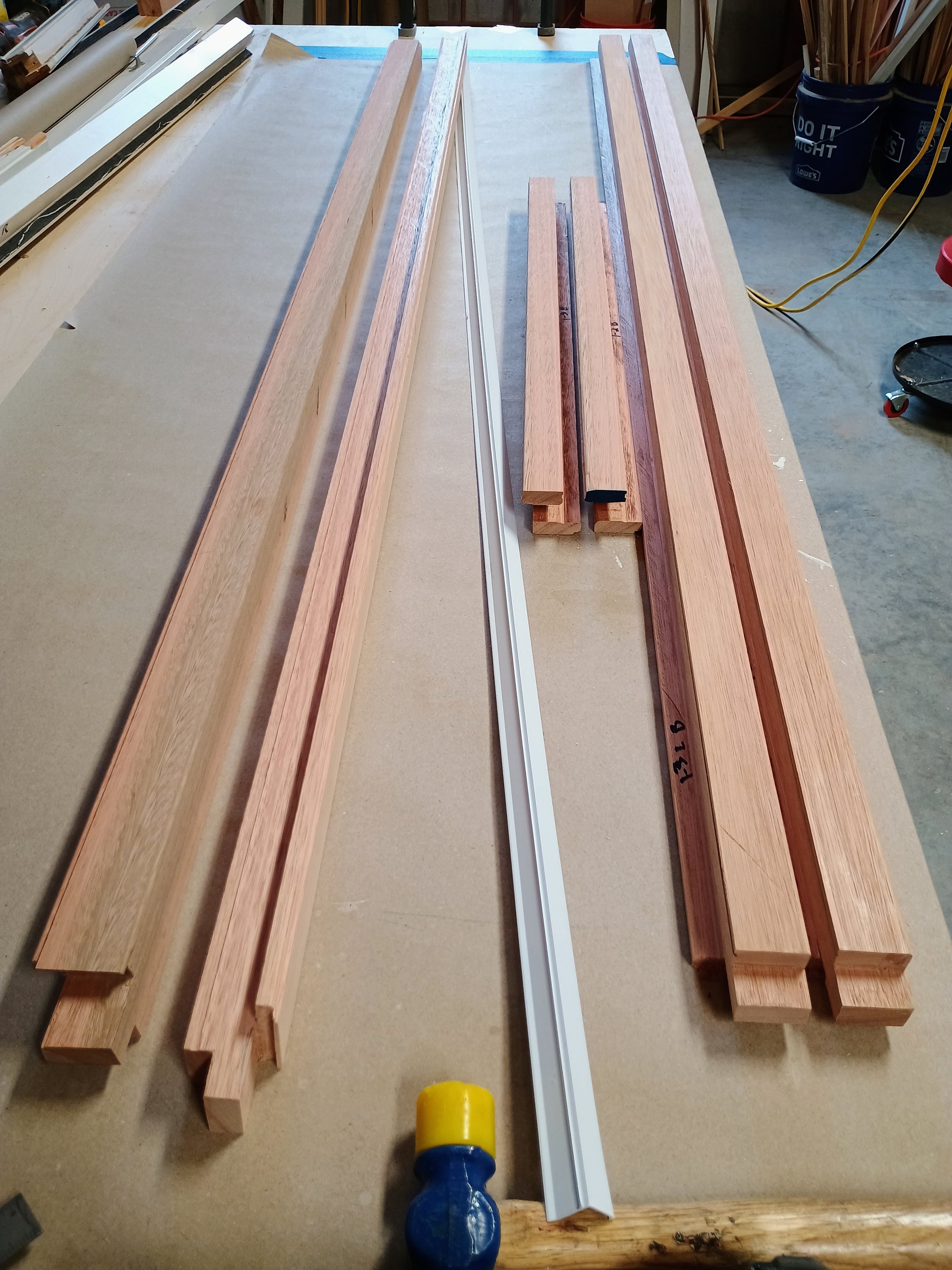 Wooden planks and metal rails laid on a workbench in a workshop.