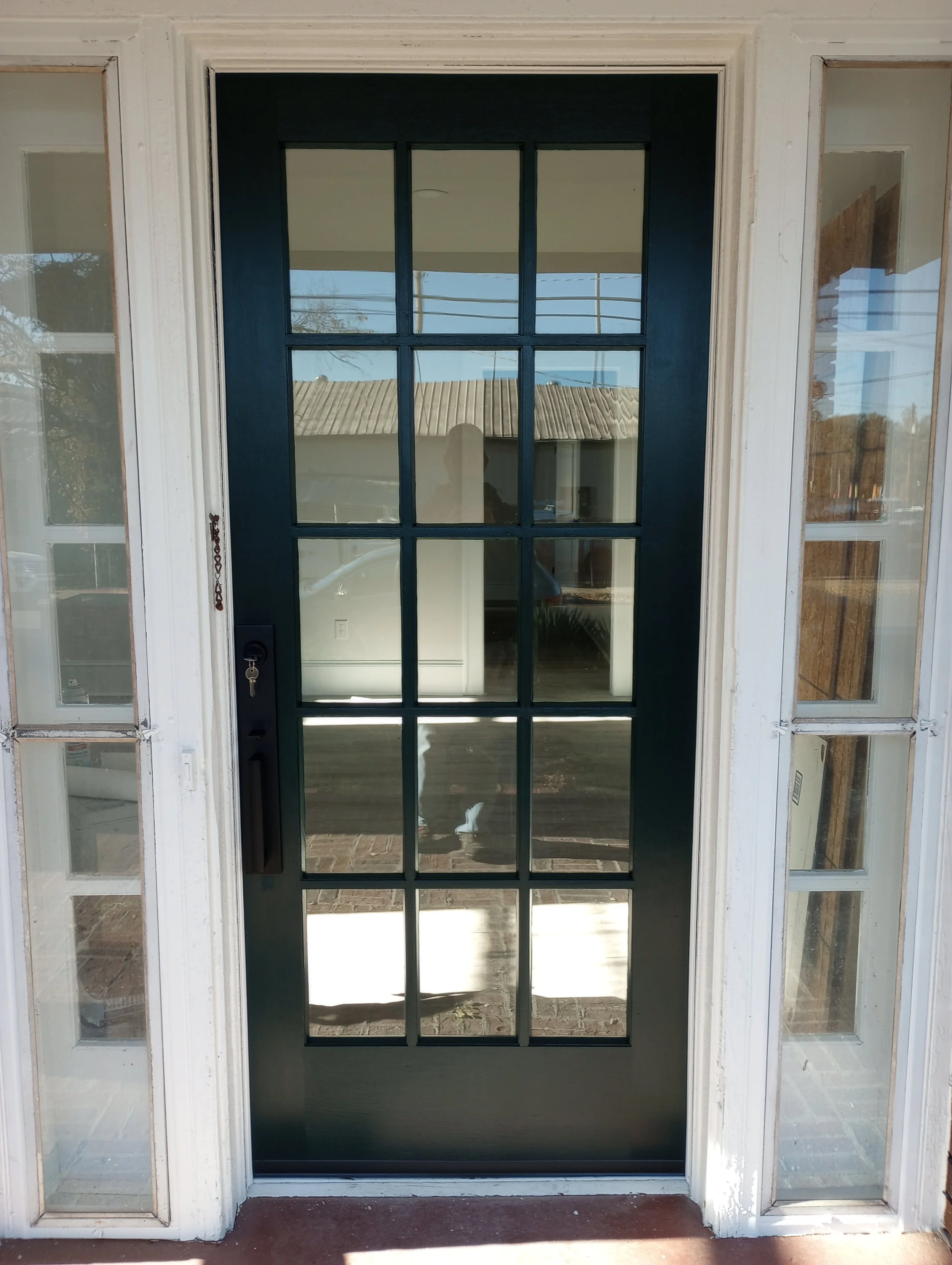 Front door with glass panes, painted dark blue, surrounded by sidelights with multiple small glass panes, and a white frame.