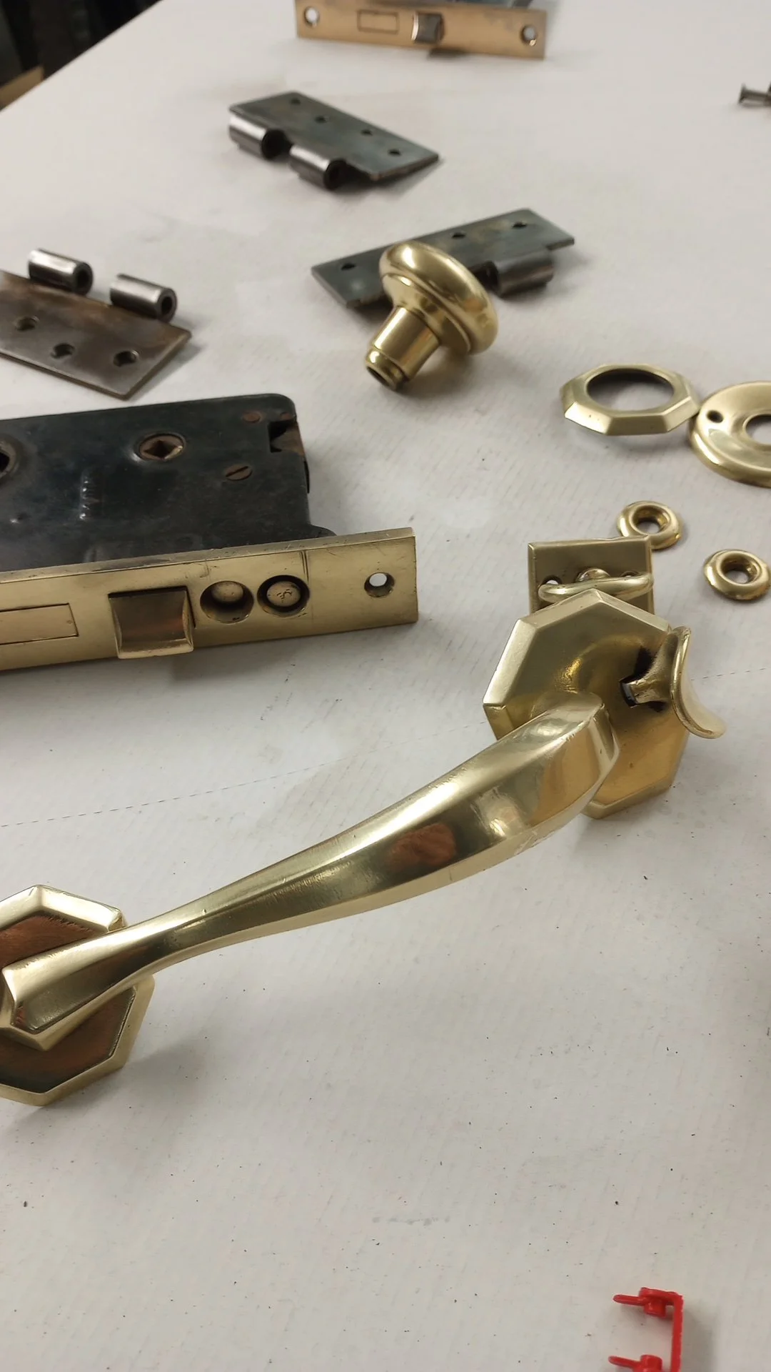 Various door hardware parts, including a brass door handle, locks, and escutcheons, arranged on a white surface.