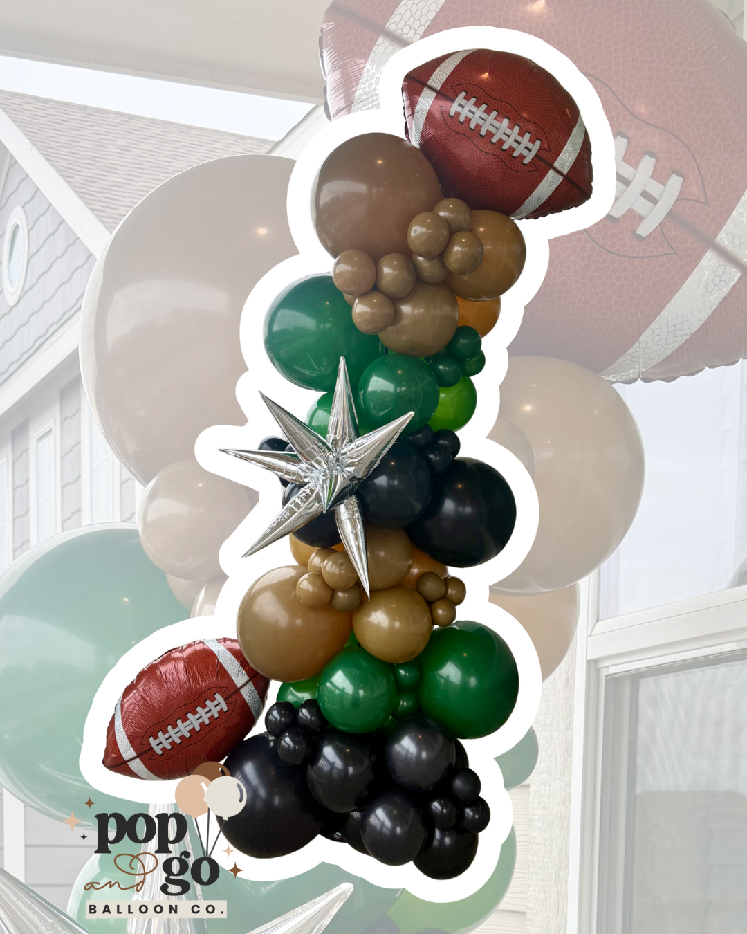 Balloon display featuring football-shaped balloons, and various colored round balloons in black, green, beige, and brown, with star-shaped metallic balloons, arranged indoors near windows.