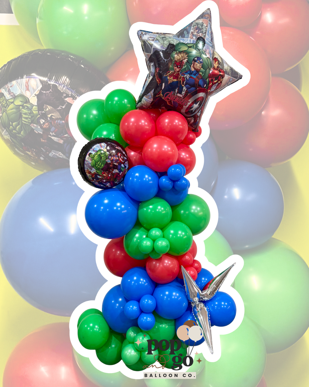 Colorful balloon arrangement with superhero-themed balloons, including characters like Hulk, Captain America, Iron Man, and Black Panther, topped with a star-shaped balloon and a round balloon featuring Marvel superheroes.