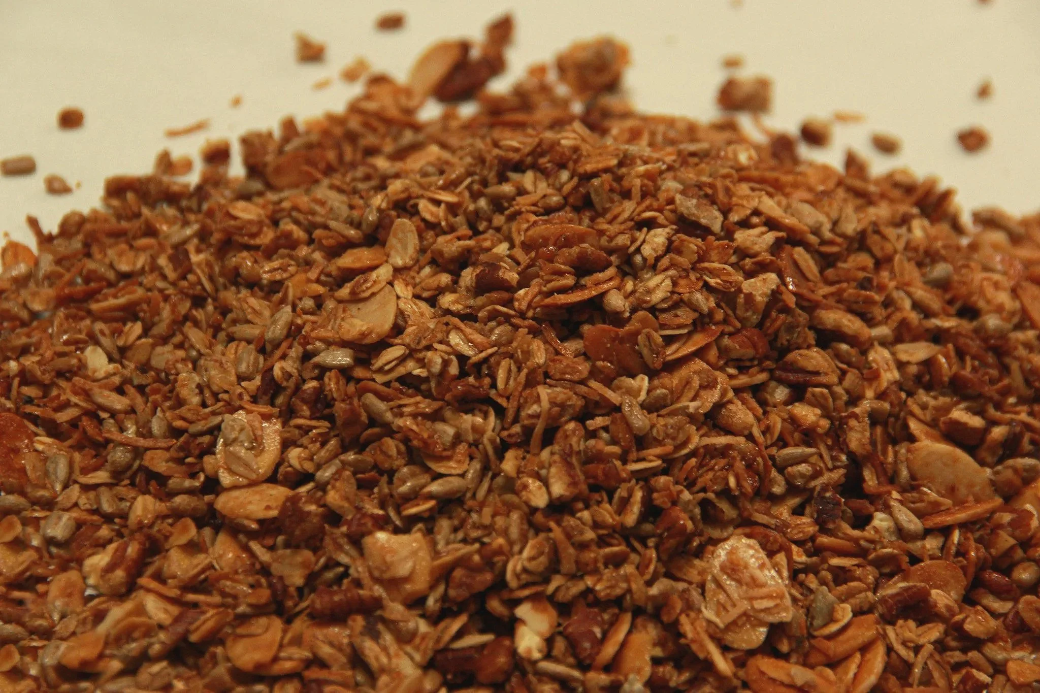 Close-up of a pile of granola or toasted oats on a white surface.