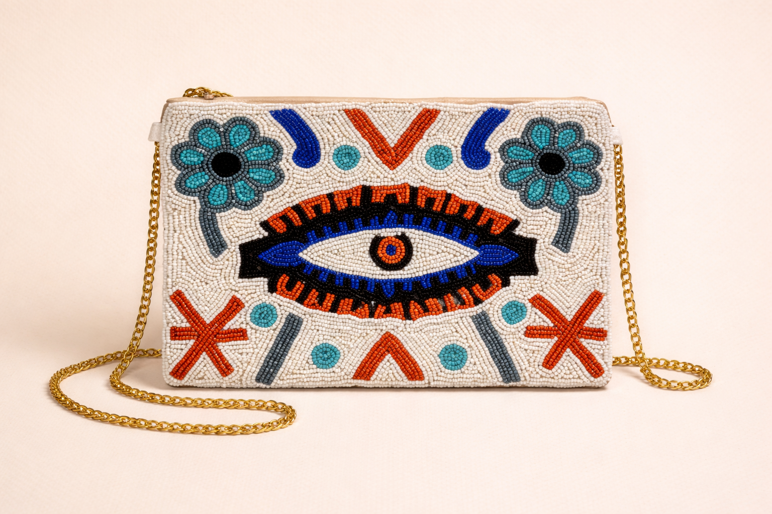 Beaded handbag with embroidered eye and floral patterns, gold chain strap, on a light background.