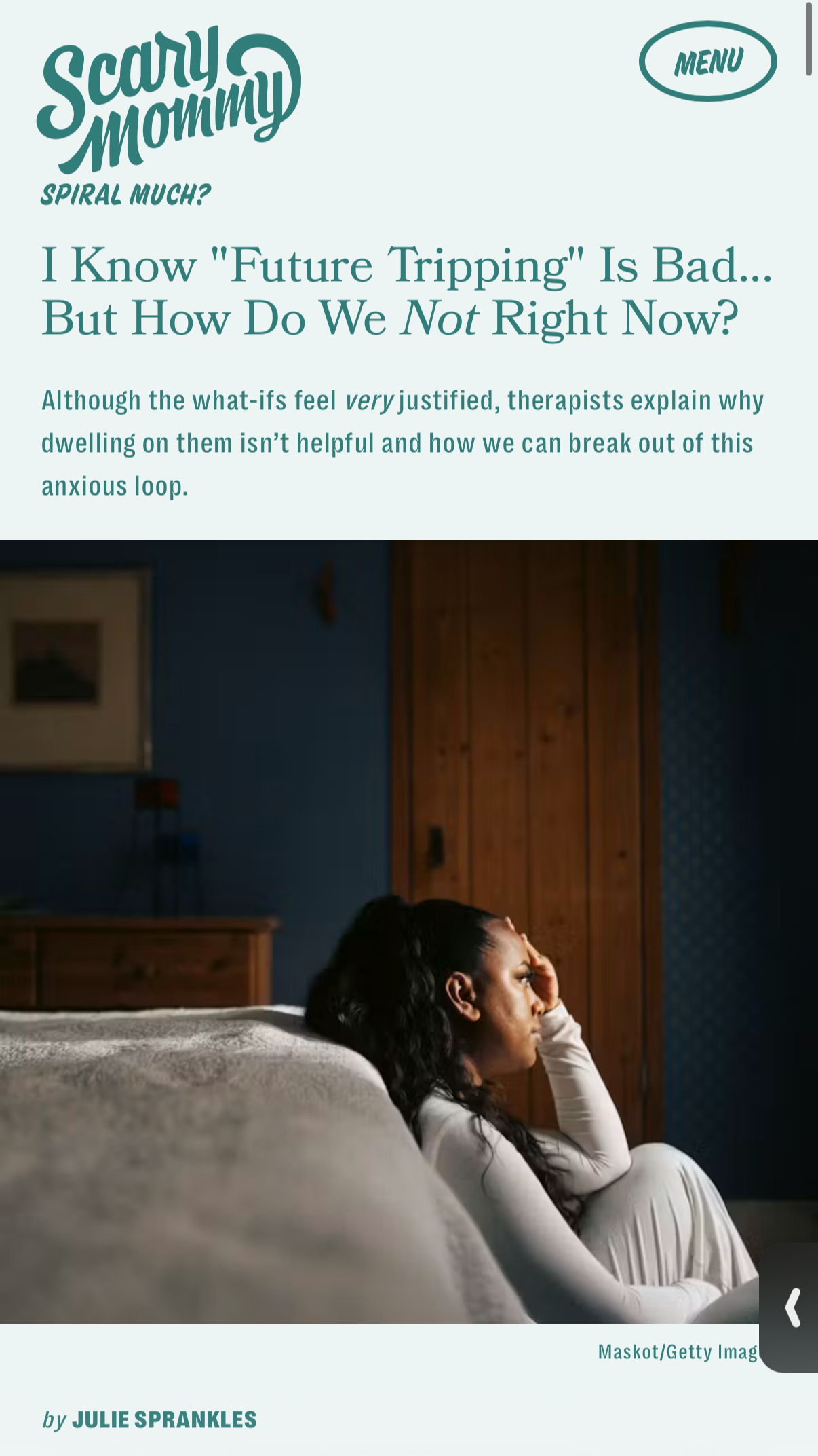 A woman with dark curly hair sitting on a bed, resting her head on her hand, appearing thoughtful or worried.