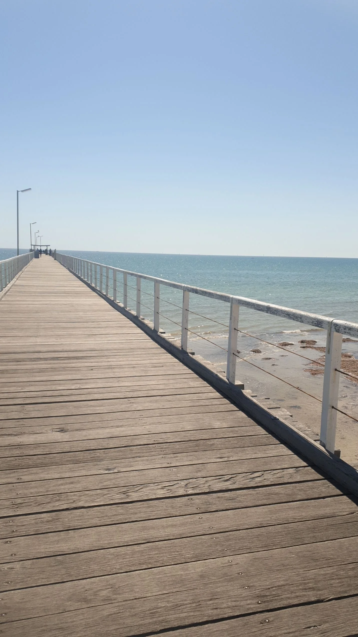 Wooden jetty extending over the ocean at Semaphore Beach, creating an open and welcoming atmosphere.