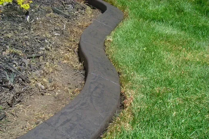 Custom textured curbing separating grass and mulch in yard