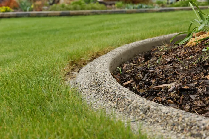 Exposed aggregate concrete curbing in rural backyard landscaping