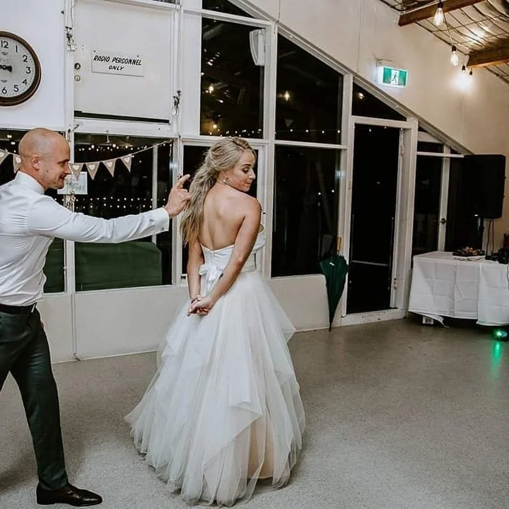 A bride and groom dancing their first dance at a reception hall.