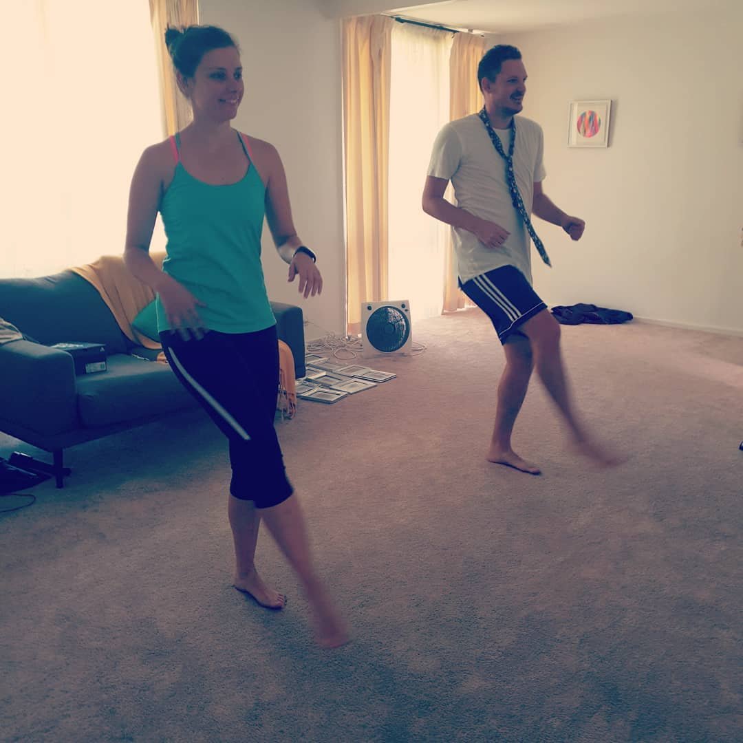 Two people, a woman and a man, are dancing in a living room, rehearsing their first dance for their wedding.