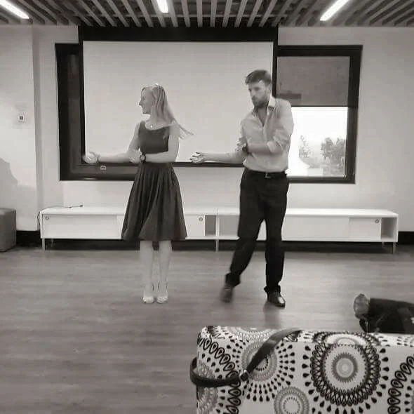 A man and woman rehearsing their wedding dance facing each other.
