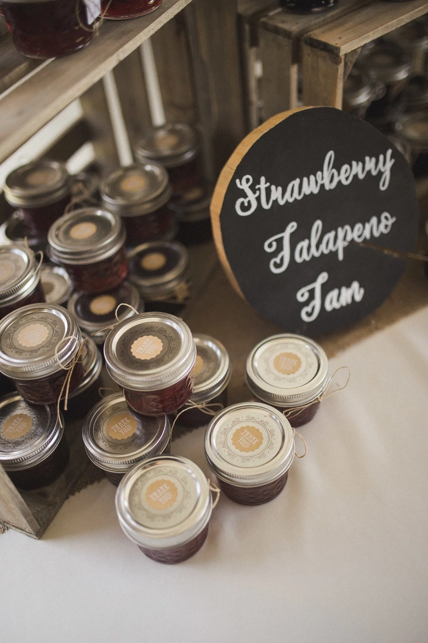 Small strawberry and jalapeno jam jars display on a table with a sign