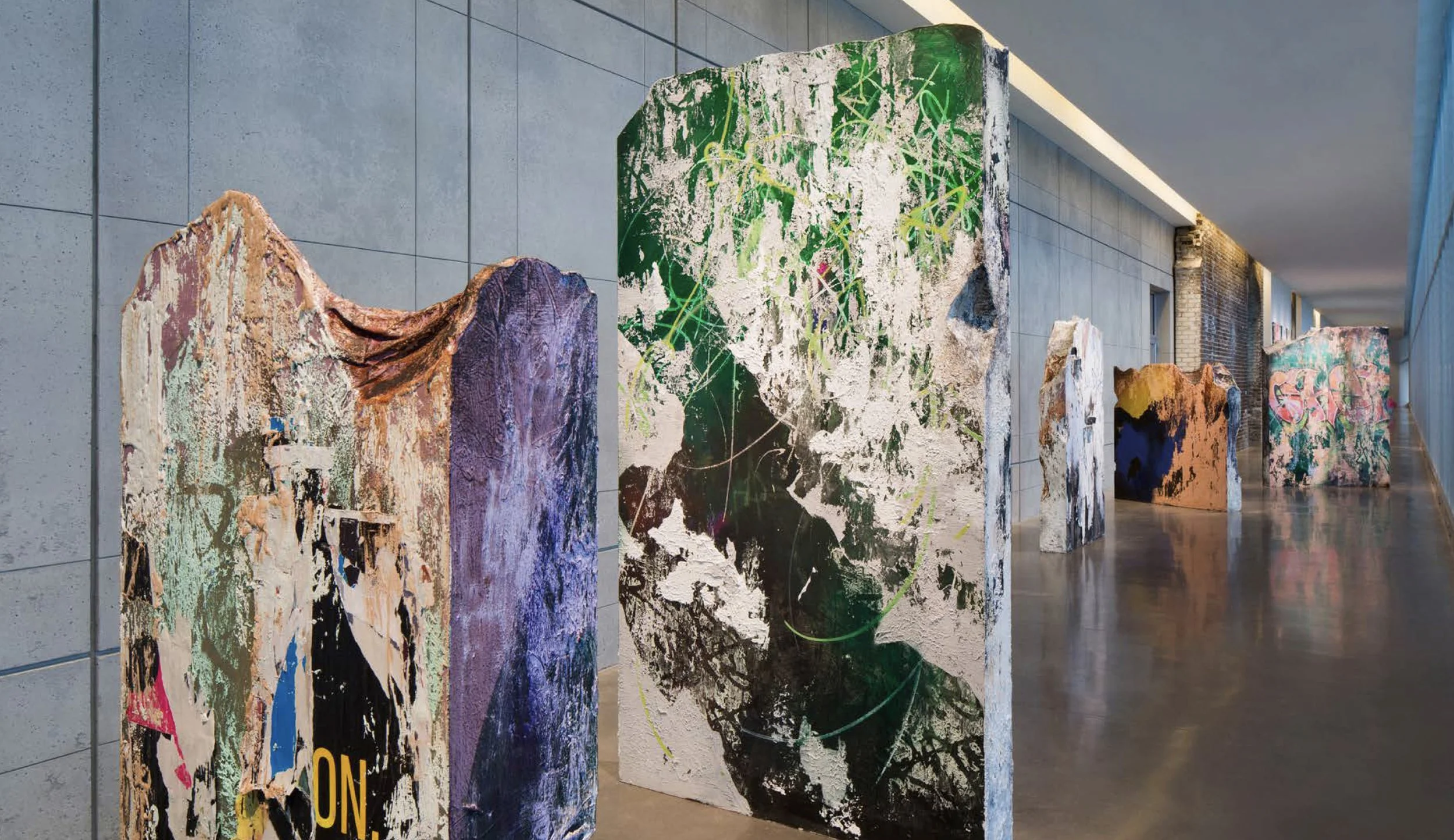 Art installations featuring large, abstract painted panels arranged along a wall in an indoor gallery space.