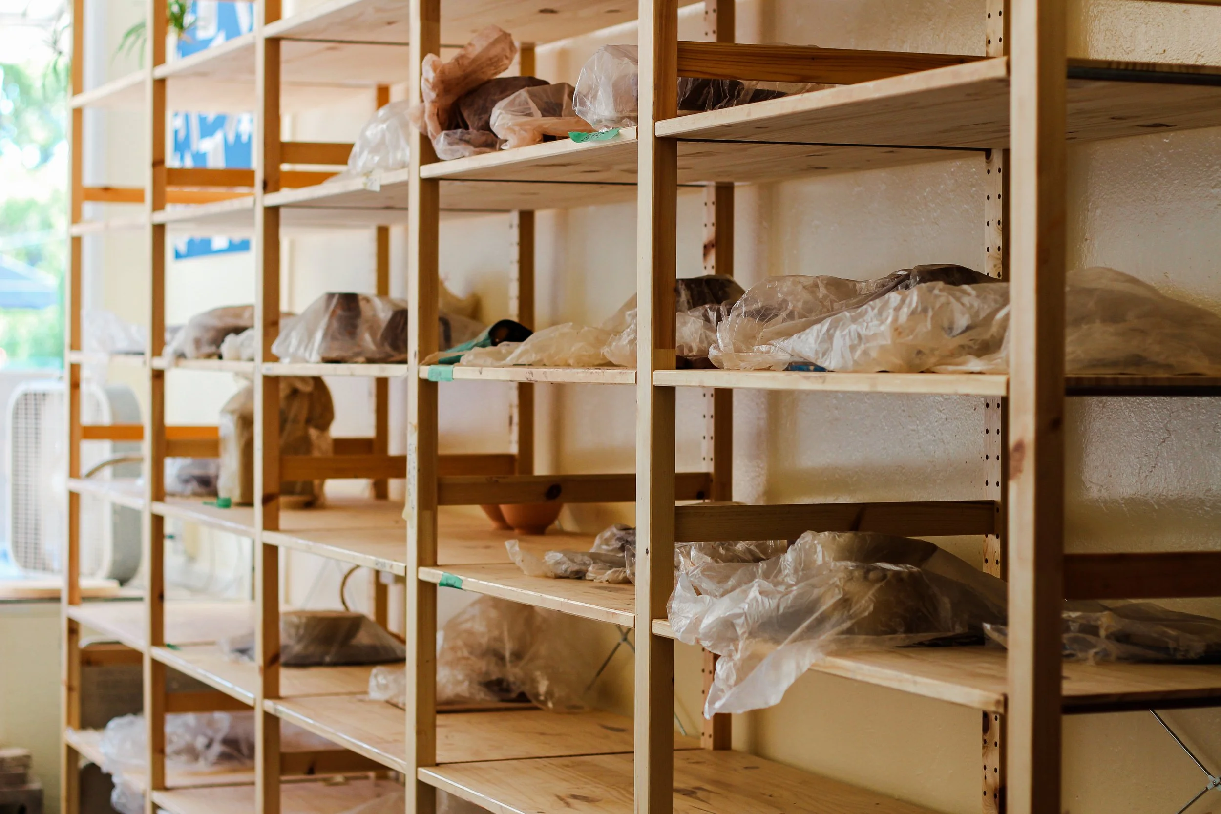 Empty wooden shelves with plastic-wrapped items inside a room.